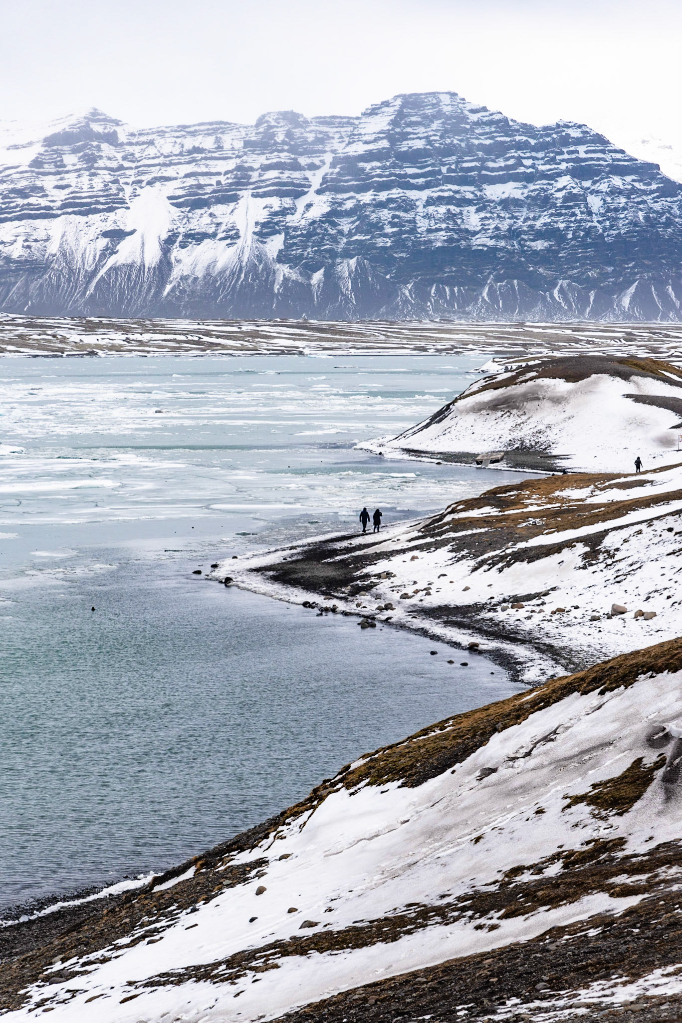 People walking along the coastline of the Jokulsarlon laggoon in Iceland