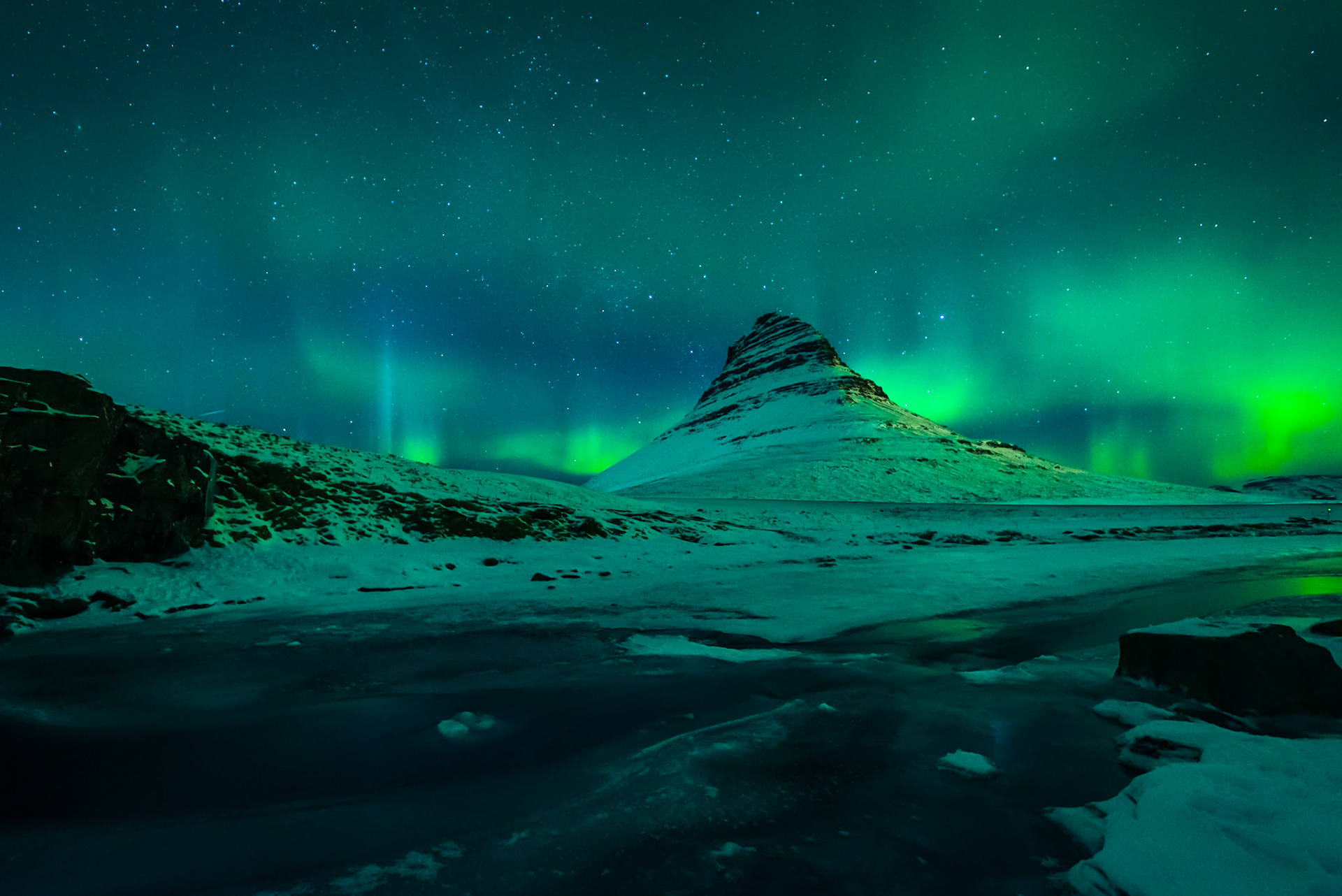 Northern lights over Kirkjufell and Kirkjufellsfoss waterfall in Iceland