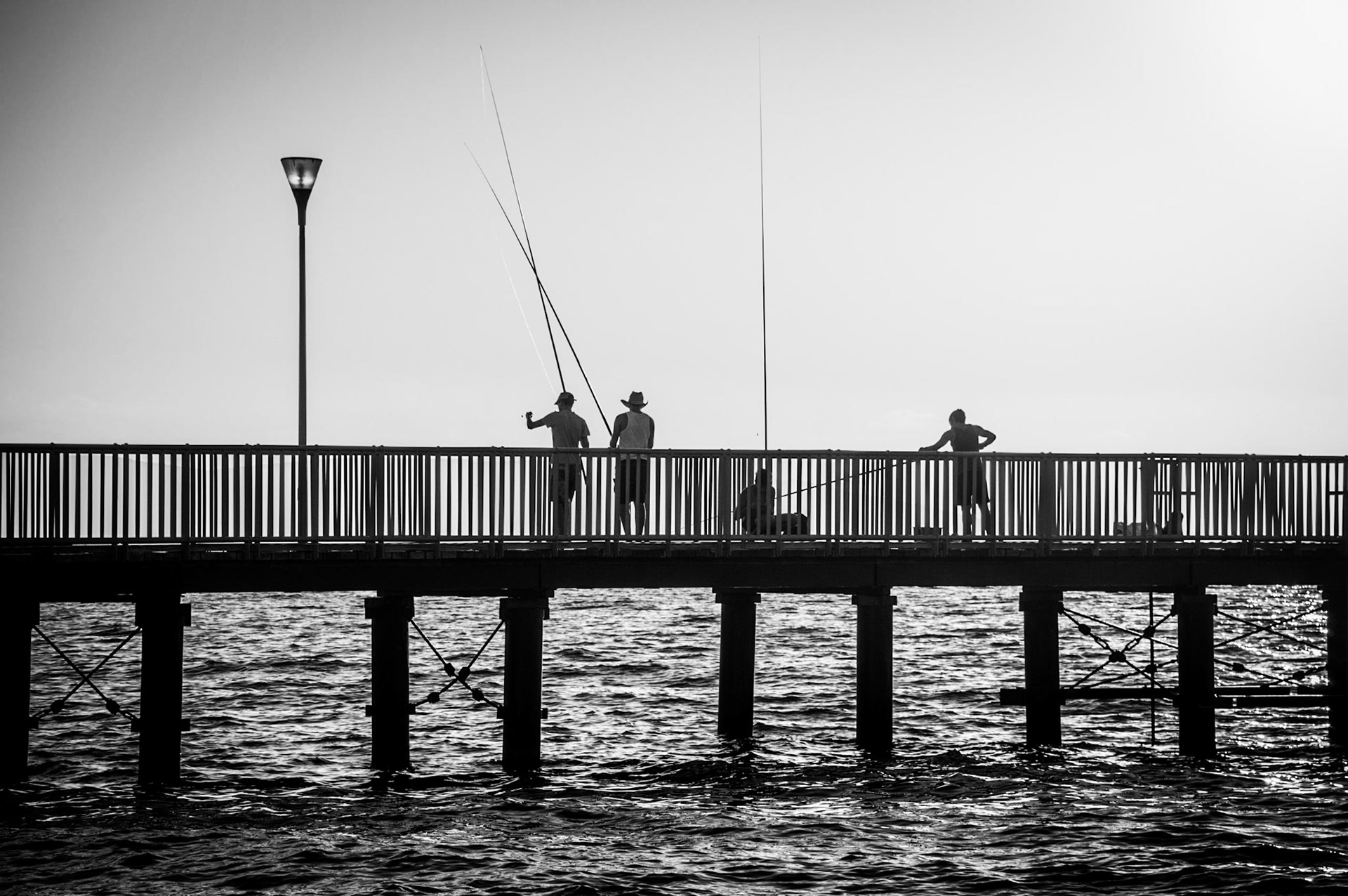 People fishing in the sunset at Limni Pier in Paphos Cyprus