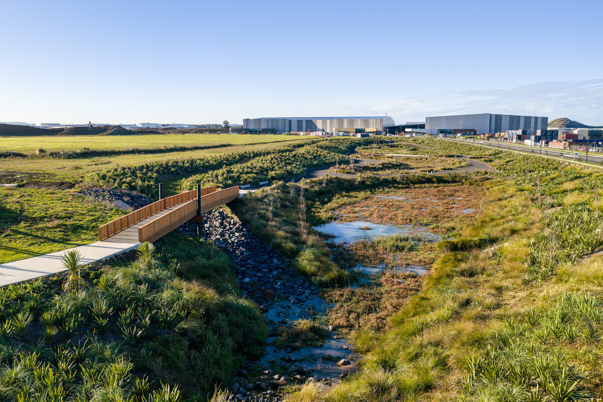 JKGL 6 Green Star commercial warehouse development at Puhinui, Auckland, viewed across landscaped wetlands