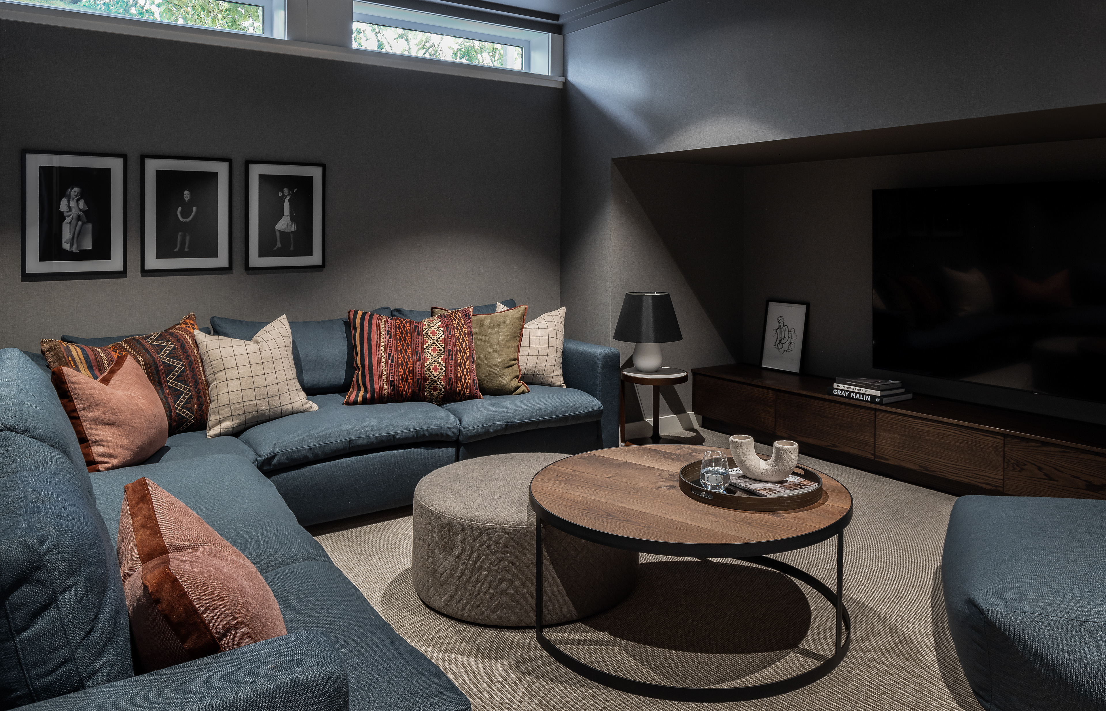 Remuera bungalow media room with deep blue sectional seating, patterned cushions and dark timber cabinetry