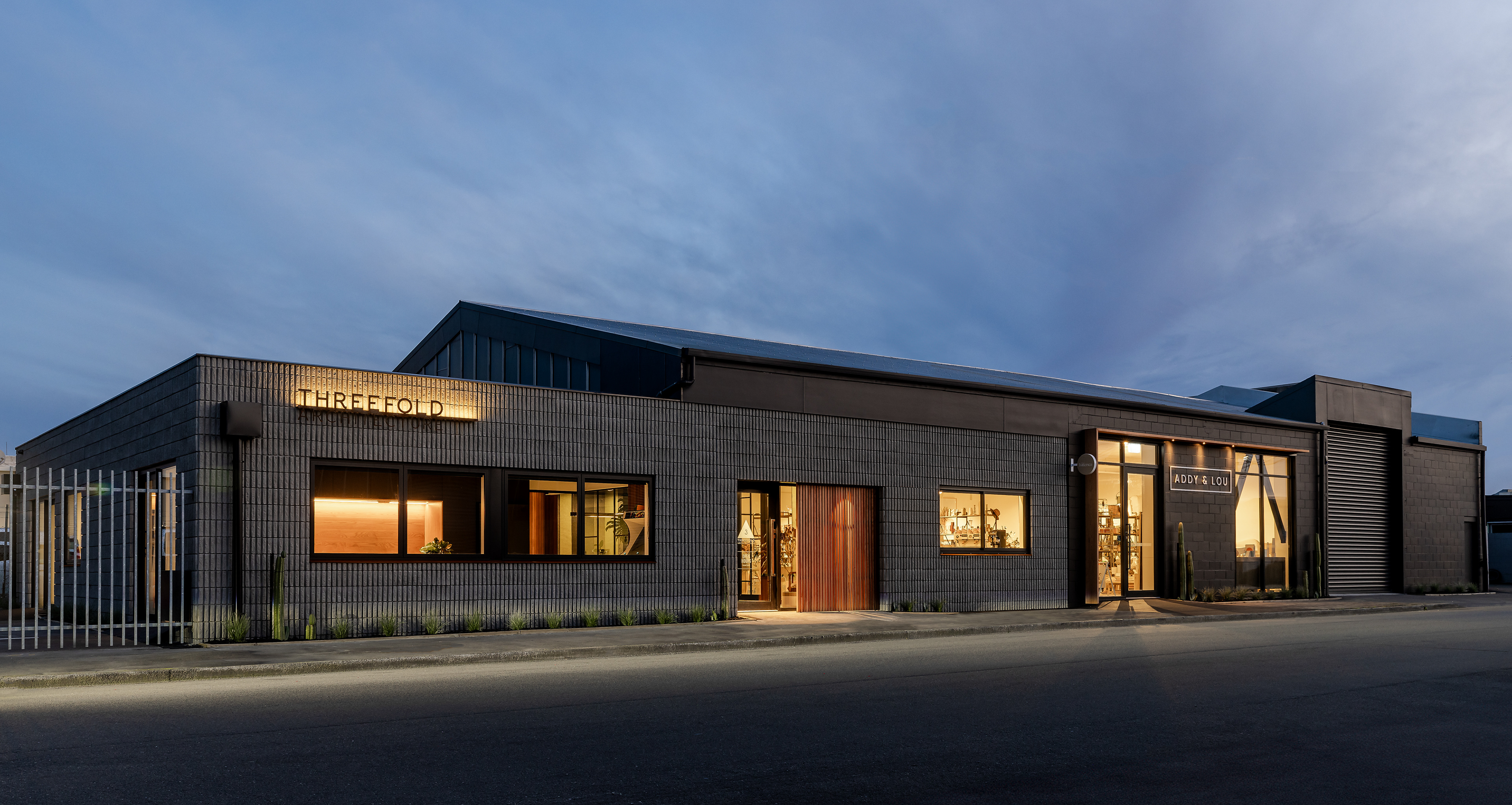 Threefold Architecture studio and office exterior at dusk with illuminated Threefold signage