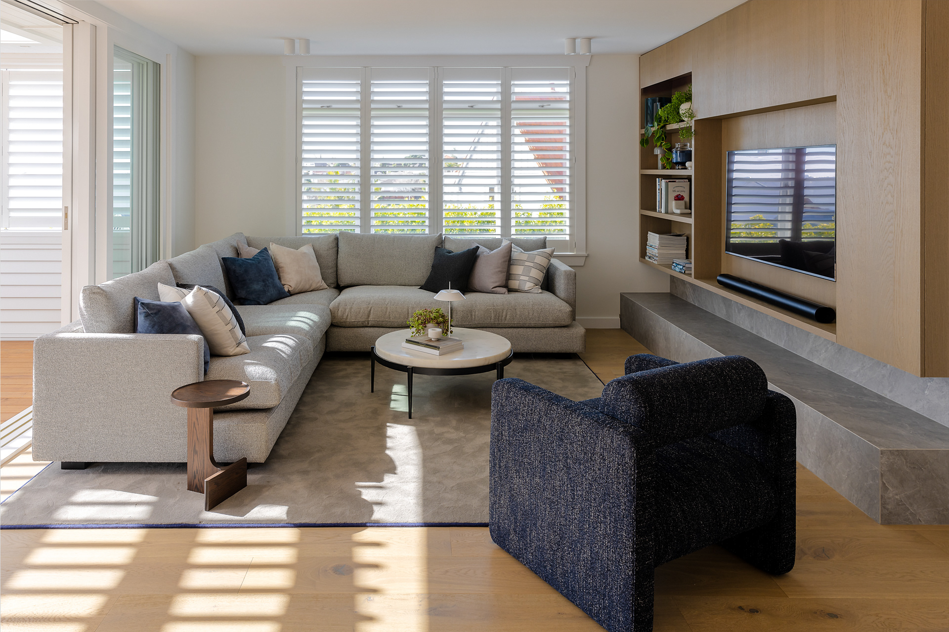 Wide view of the Codrington Residence living room with timber media cabinetry and patterned natural light