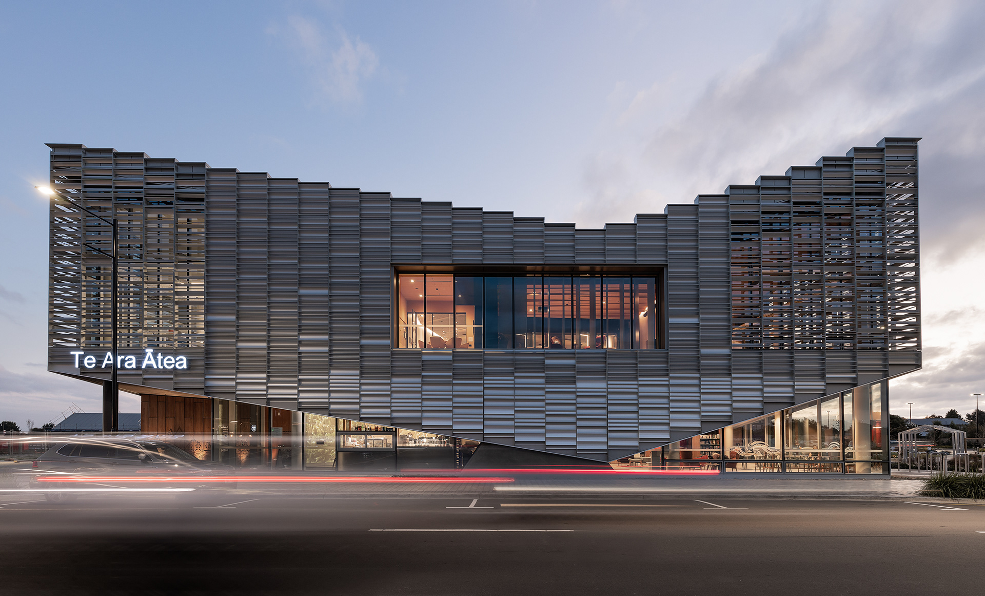 Te Ara Ātea library by Warren and Mahoney, photographed at dusk with its illuminated screened façade