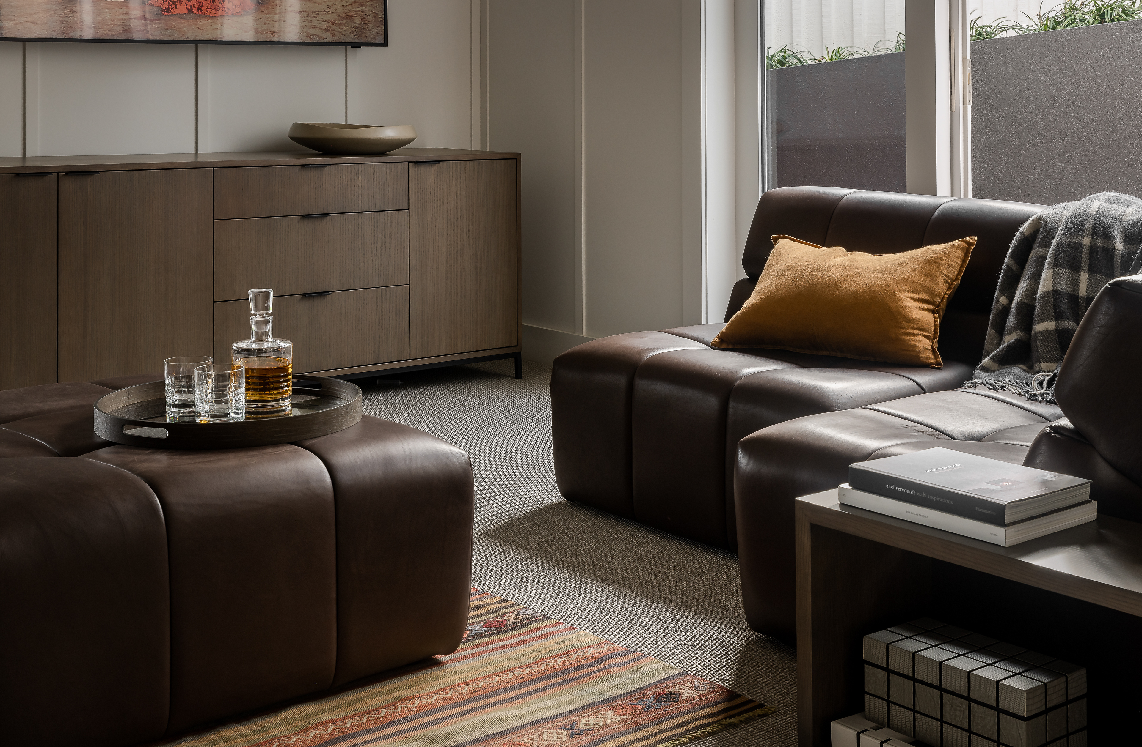 Detail of the Remuera bungalow living area with leather seating, white timber cabinetry and curated interior styling