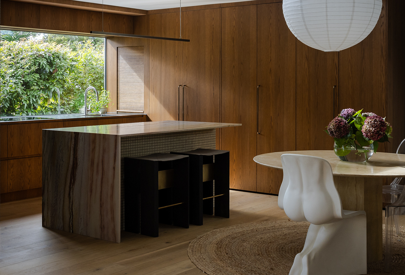 Contemporary timber kitchen interior with stone island and sculptural dining chairs