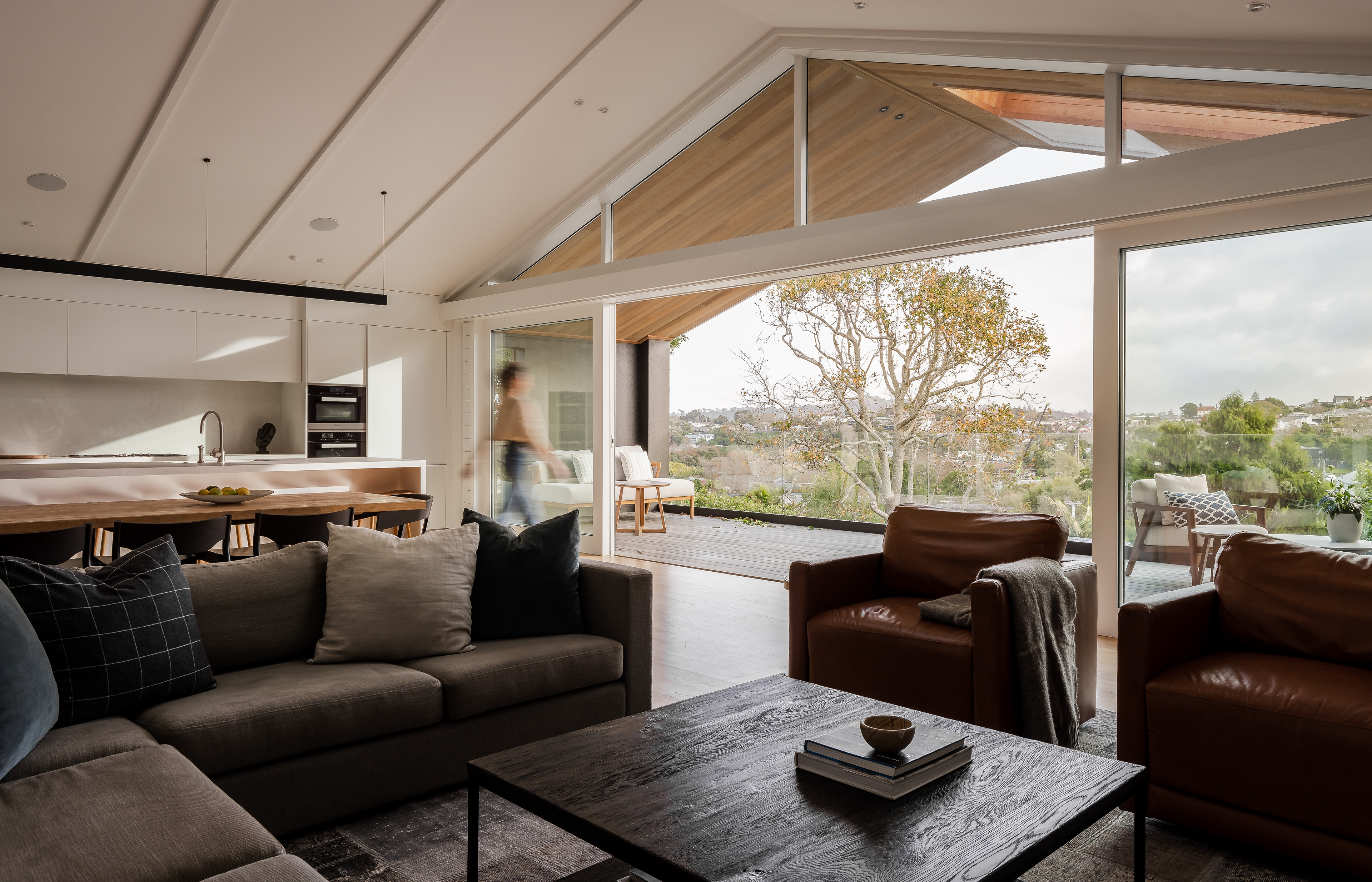 Contemporary Remuera bungalow interior opening to a sunlit outdoor terrace, with natural light across the open-plan living and kitchen spaces