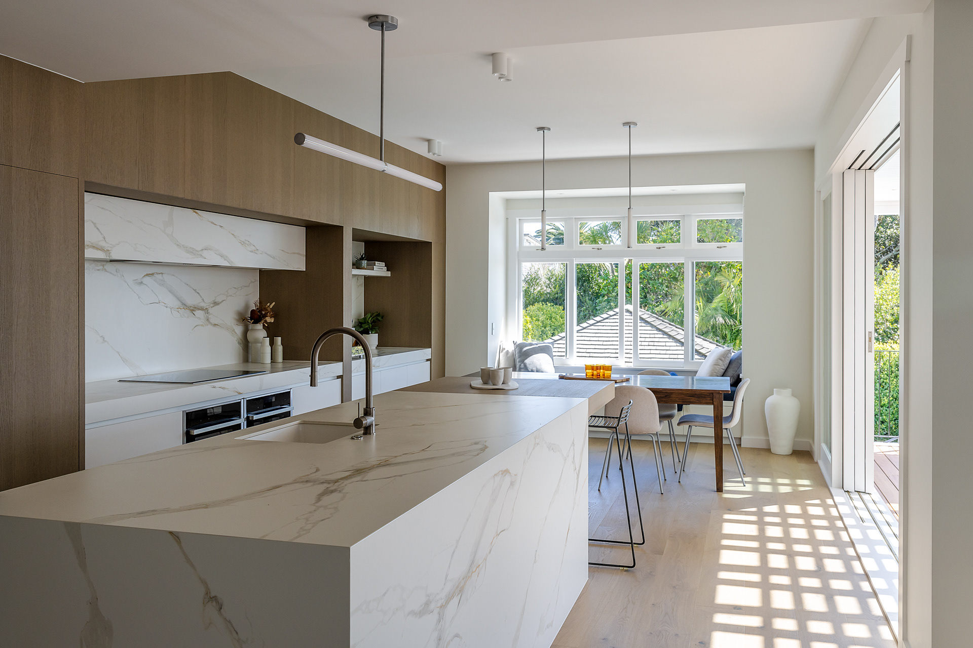 Light-filled Codrington Residence kitchen and dining area with timber cabinetry and stone island