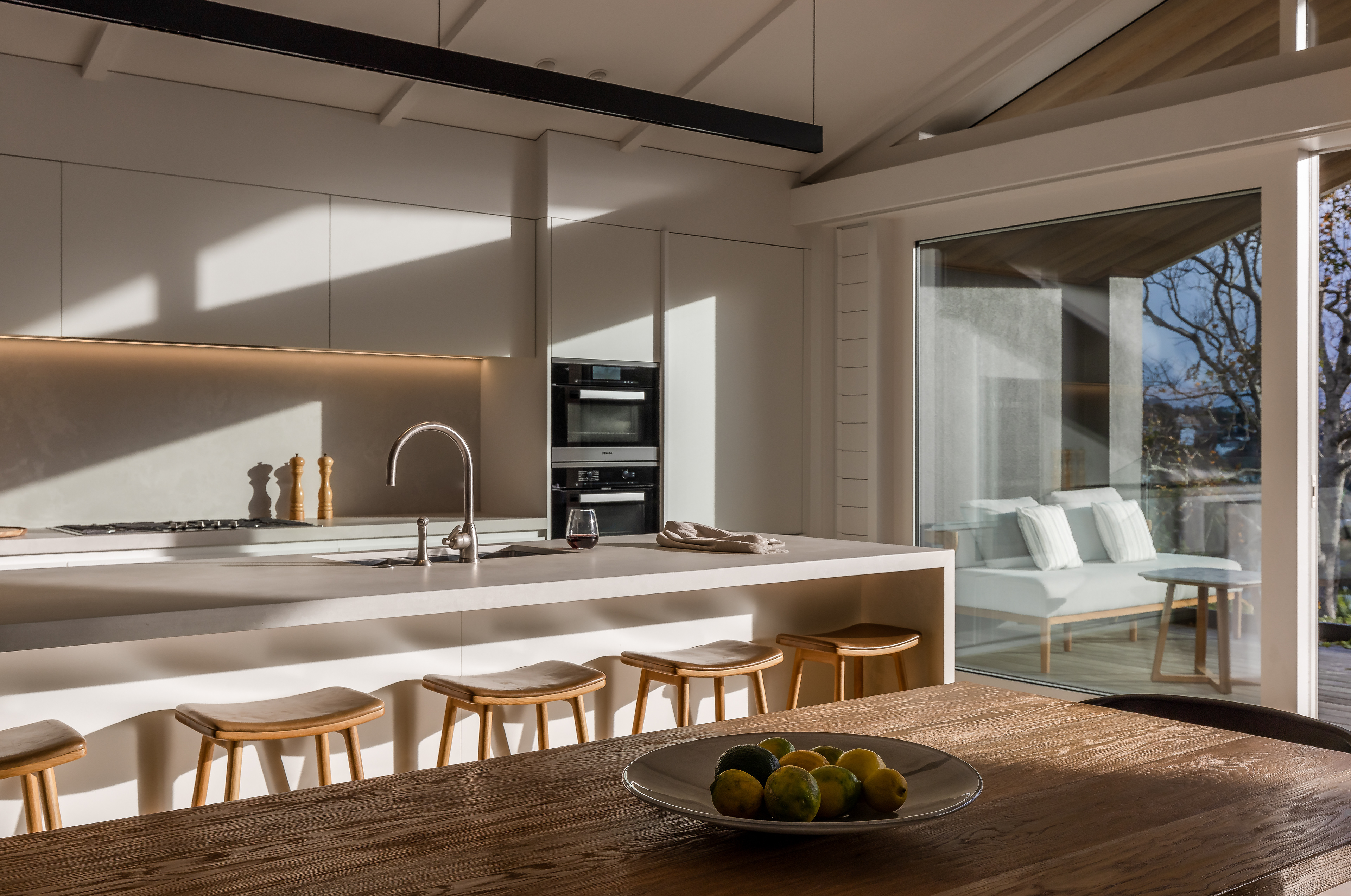 Remuera bungalow kitchen and dining area with natural light casting strong architectural shadows across the interior
