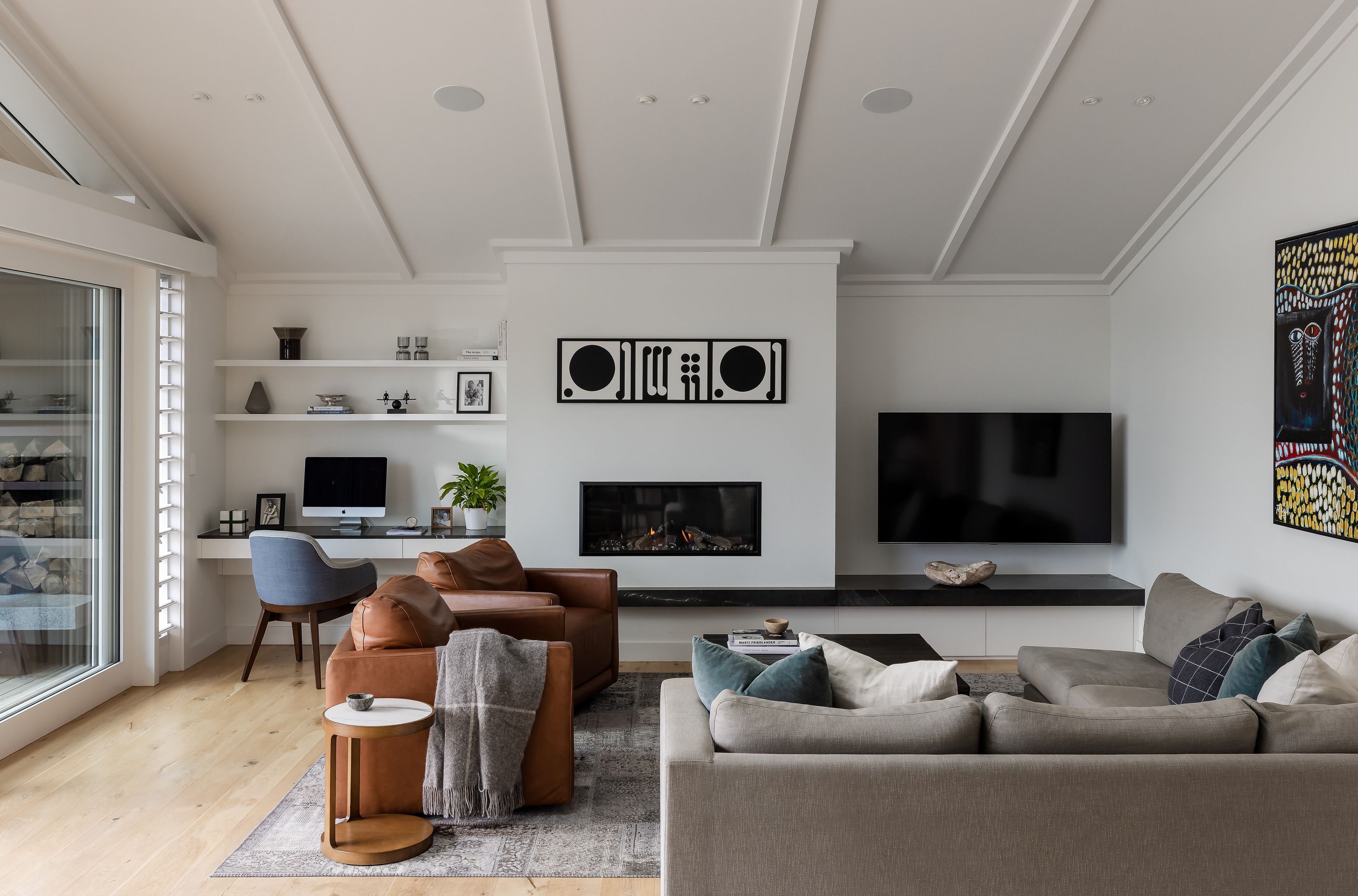 Contemporary living room with fireplace, leather armchairs, grey sofa and statement artwork