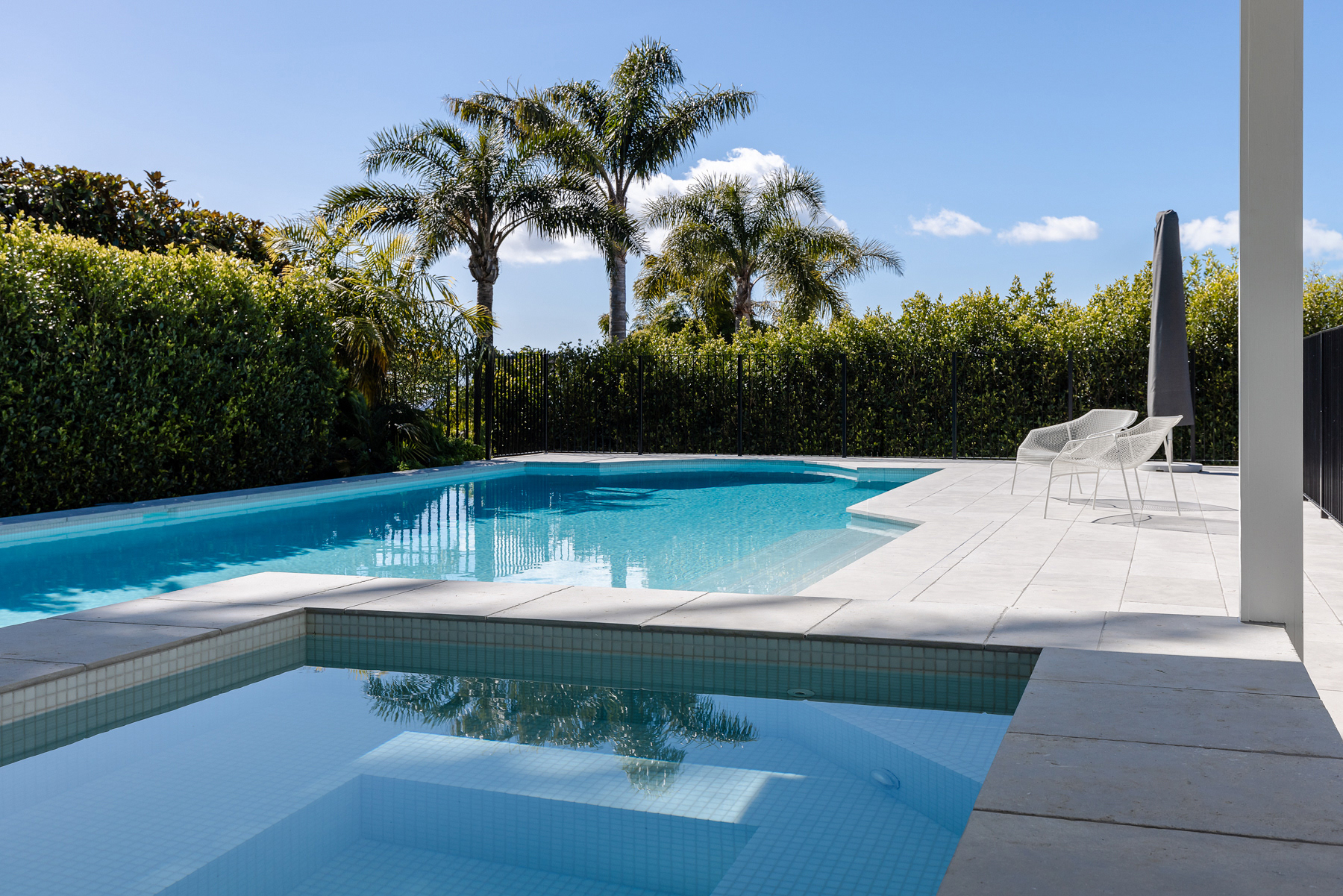 Modern residential swimming pool and spa surrounded by tropical landscaping
