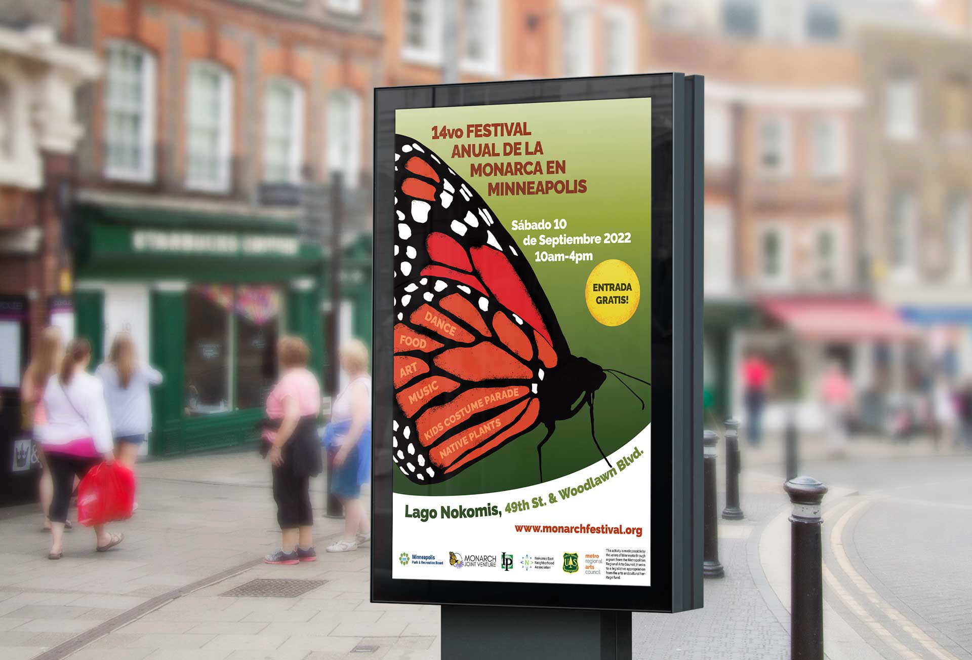 A busy city street where people walk by a large bright poster of a Monarch butterfly advertises the Minneapolis Monarch Festival.