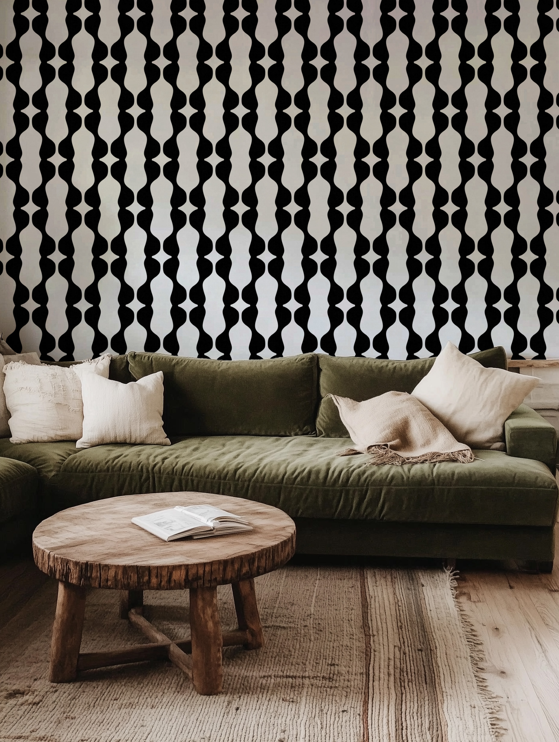 Modern black and white geometric wallpaper with vertical abstract shapes on the wall behind an olive green velvet sofa, accessorized with neutral throw pillows and a round rustic wooden coffee table on a woven rug.