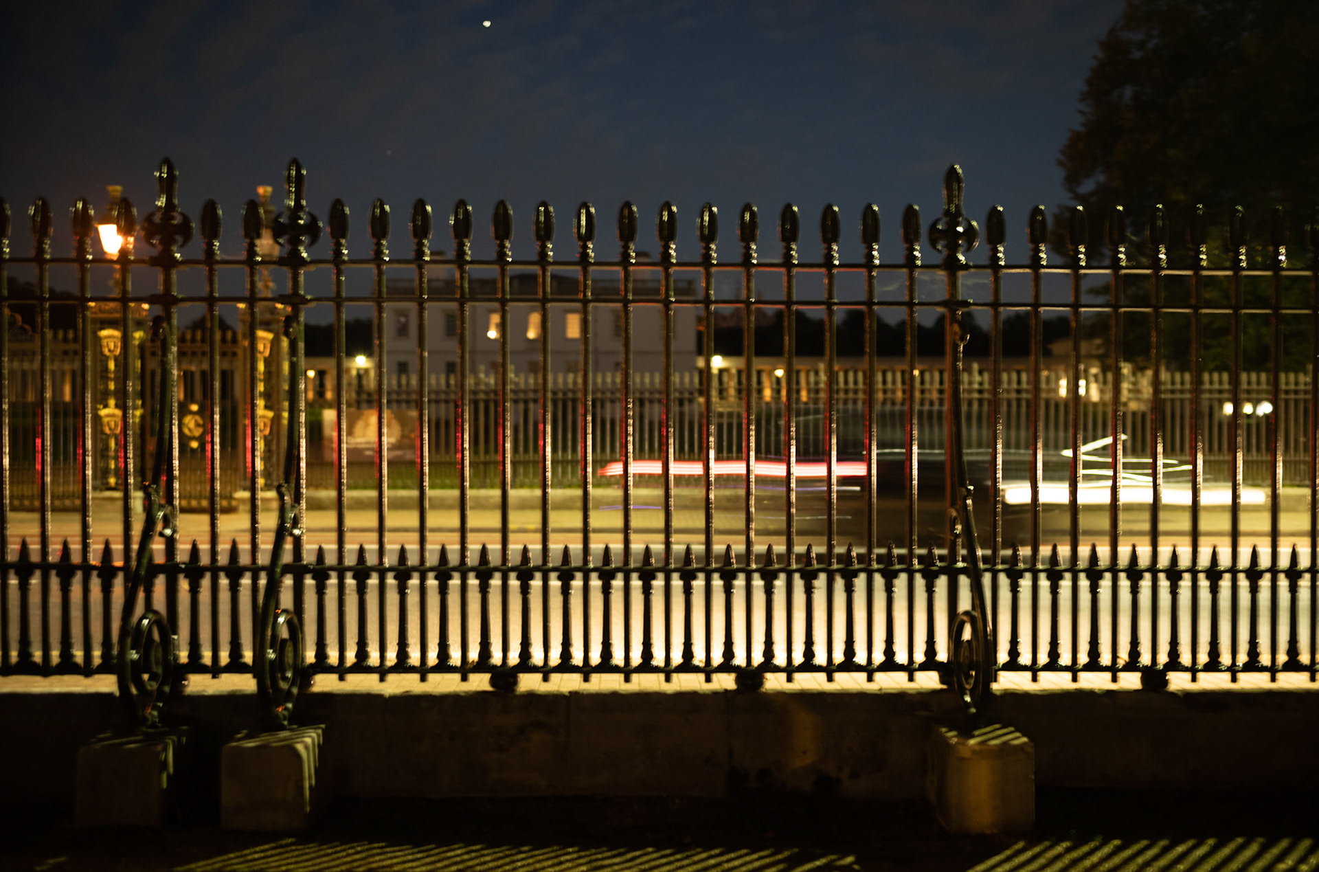 Cars outside Iron Fencing at Night