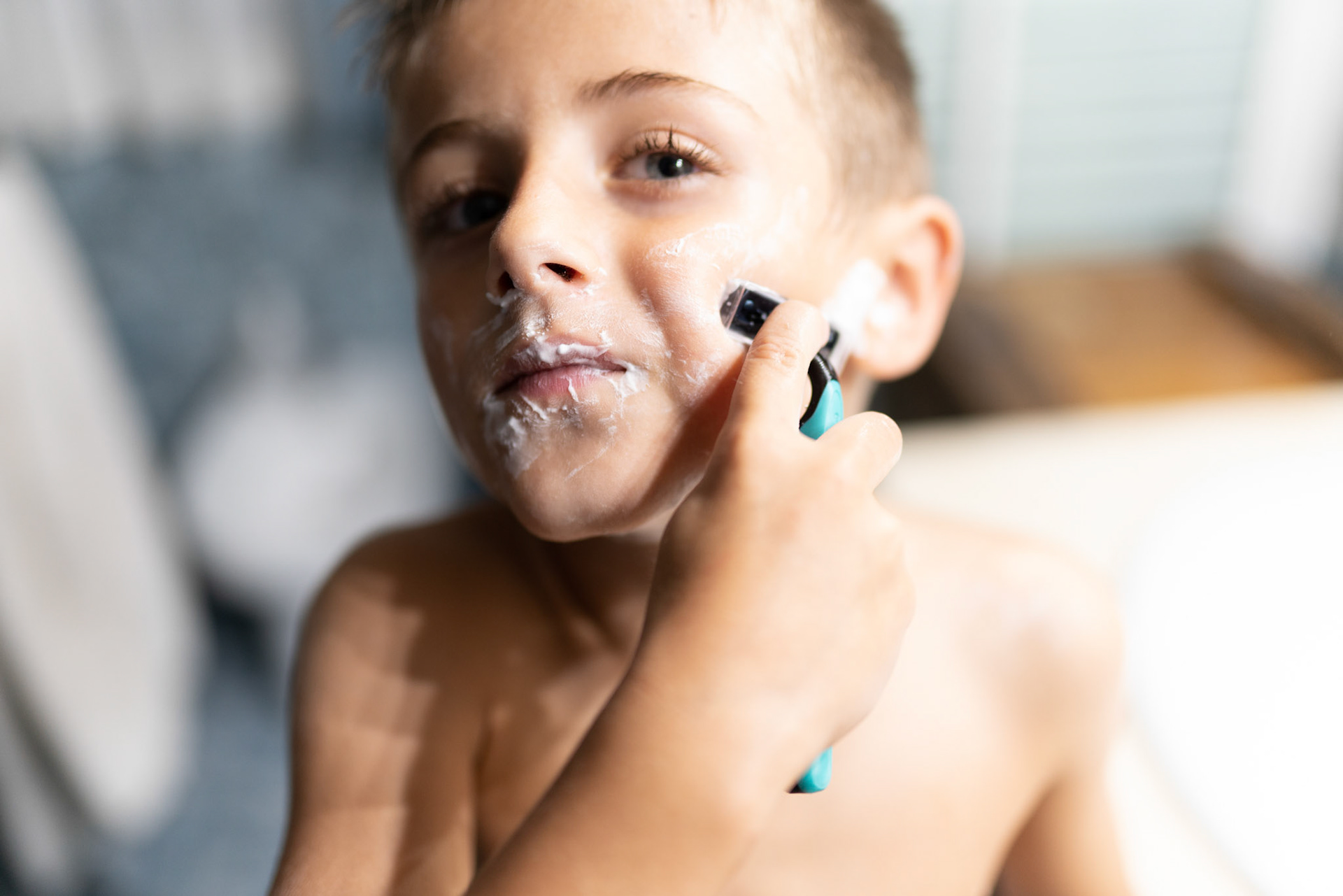 little boy shaving like an adult in the bathroom in front of the mirror