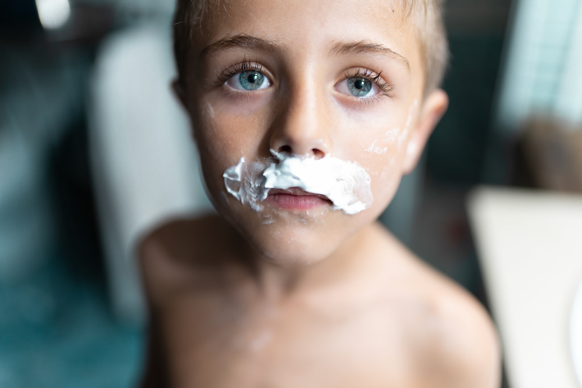 little boy shaving like an adult in the bathroom in front of the mirror