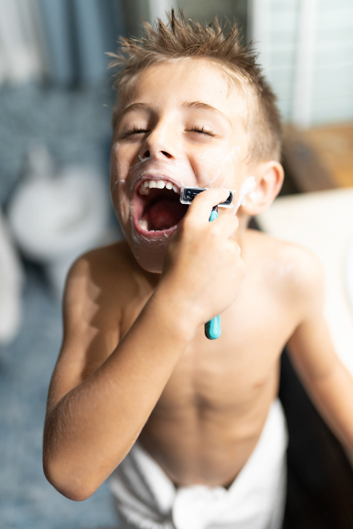 little boy shaving like an adult in the bathroom in front of the mirror