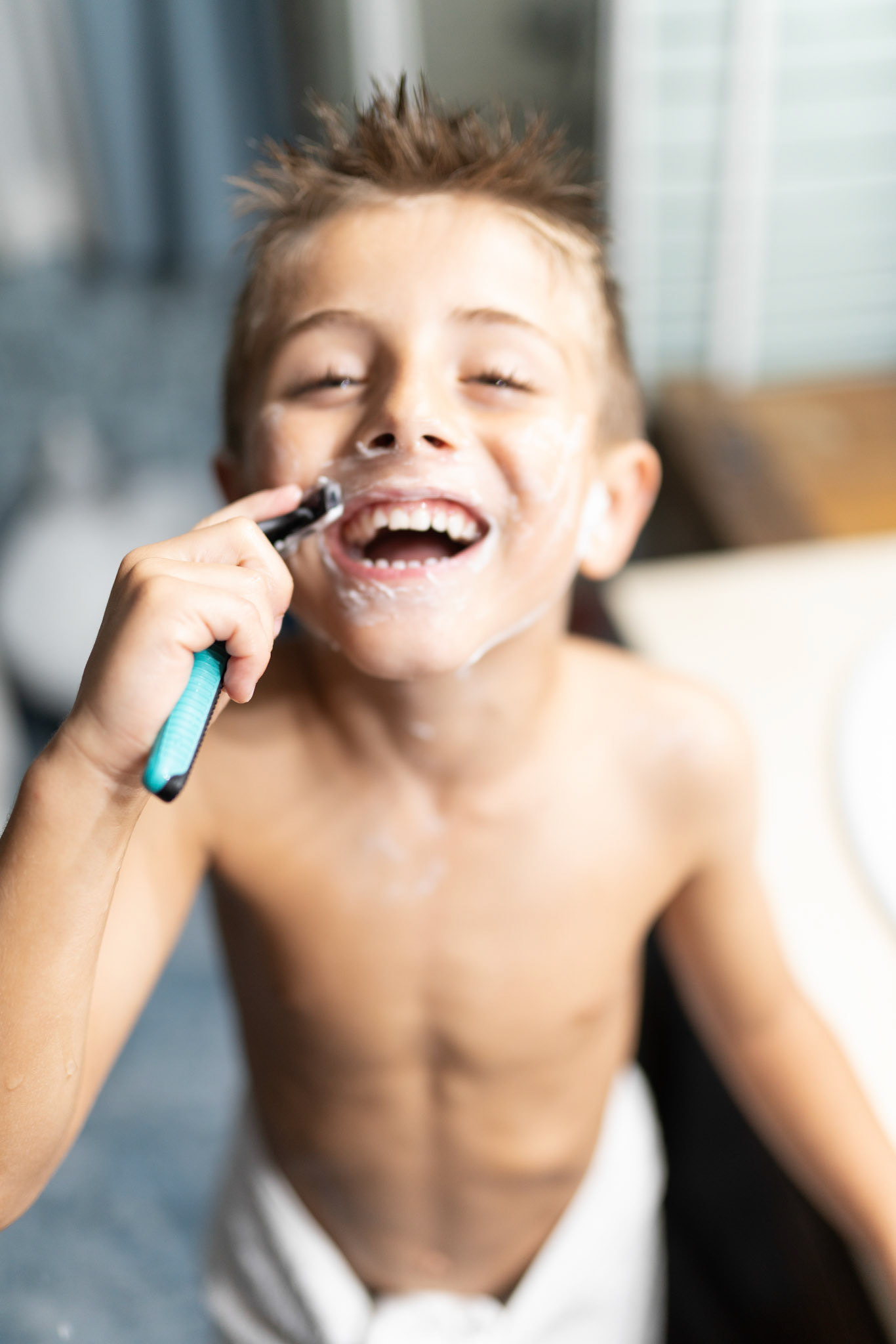 little boy shaving like an adult in the bathroom in front of the mirror