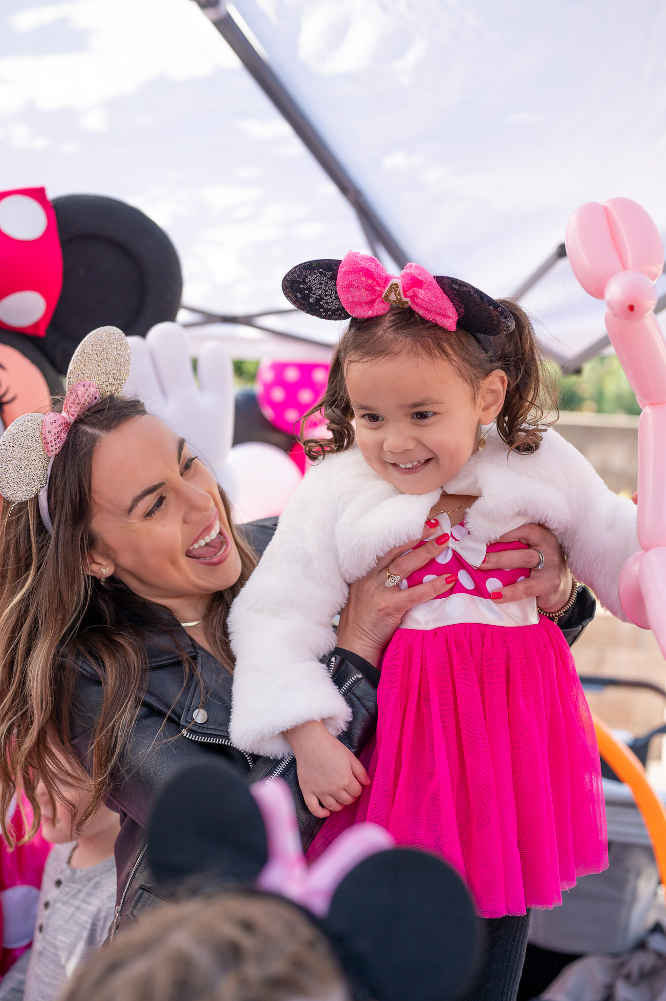 A mother lifting her daughter in the air at her birthday party.