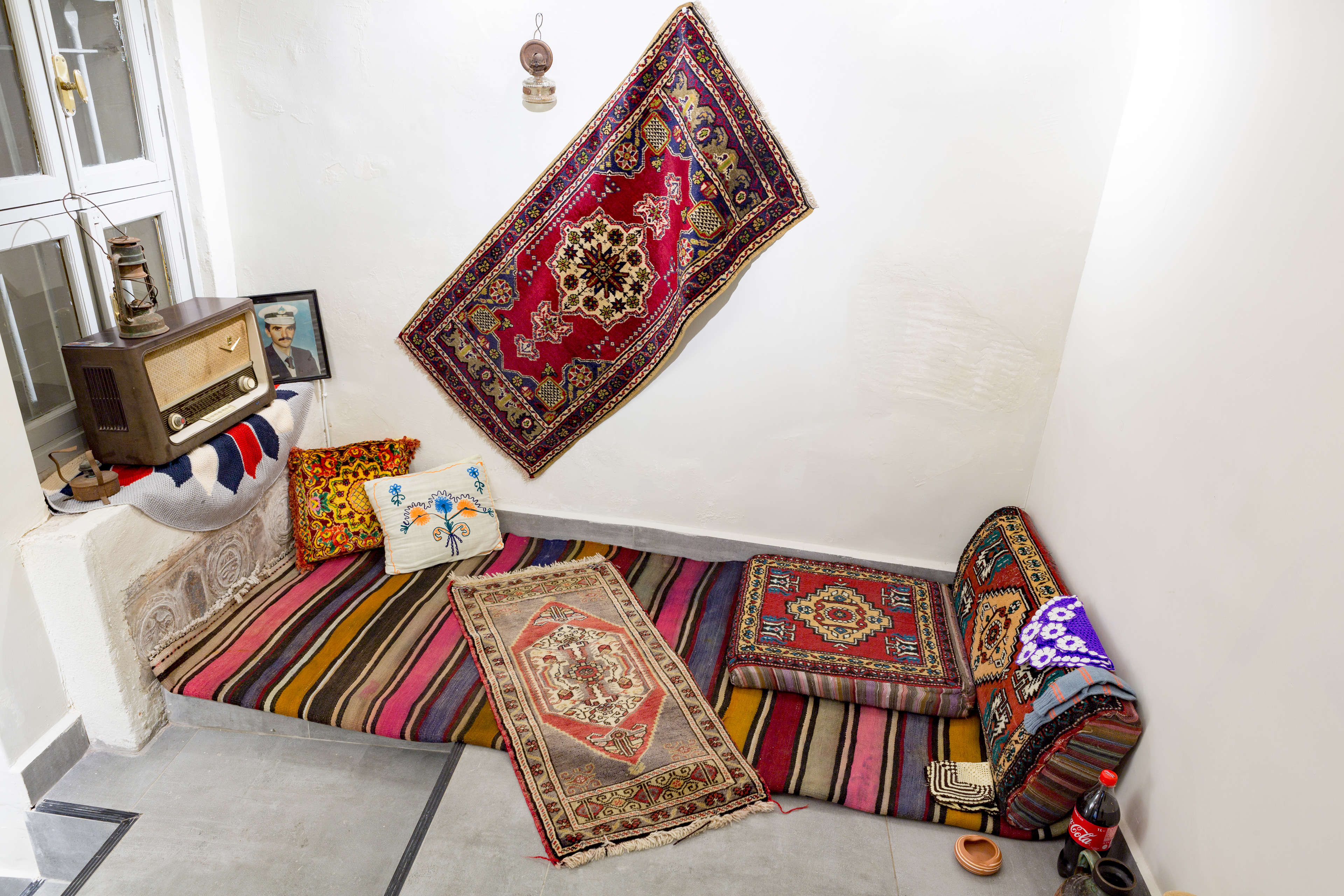  Village House, 2017, Changeable Size, old and used radio, kerosene lamps, carpet, rug, cedar, cushion, ashtray, shovel, 2 jugs, hand-knitted cloths, Coca Cola. Independent Art Foundation Art Gallery, Istanbul. Photo: İsmail Coşkun.