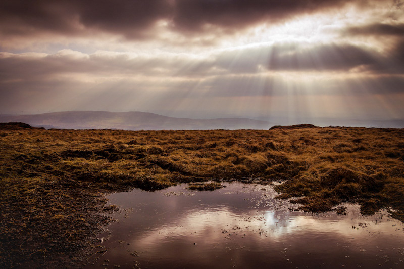 Slieveanorra Mountain landscape in golden sunset light. Hazy layers of red and brown hills are visible.
