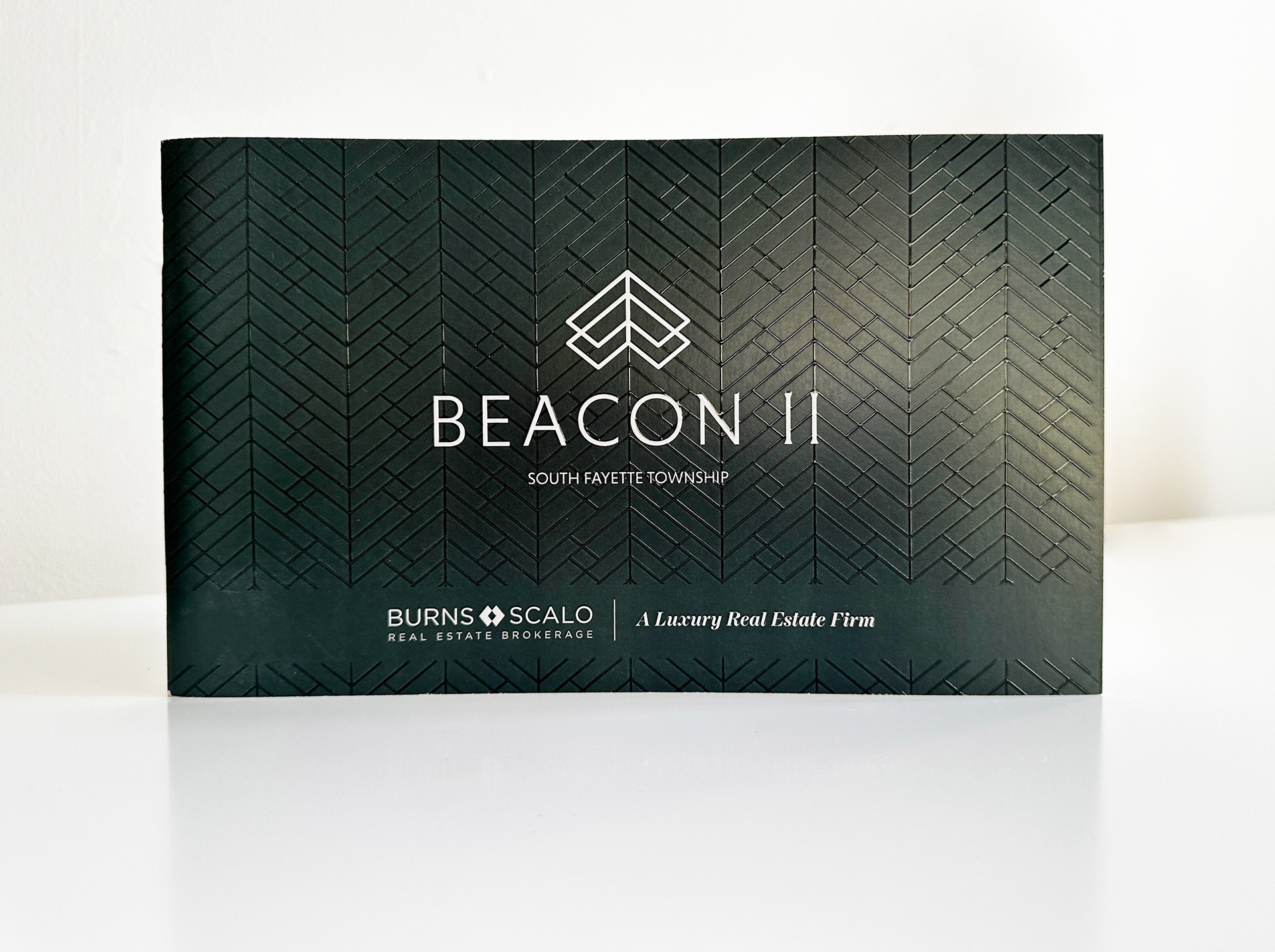 Beacon II Lookbook standing up on a white background. Lookbook is green with textured raised lines. 