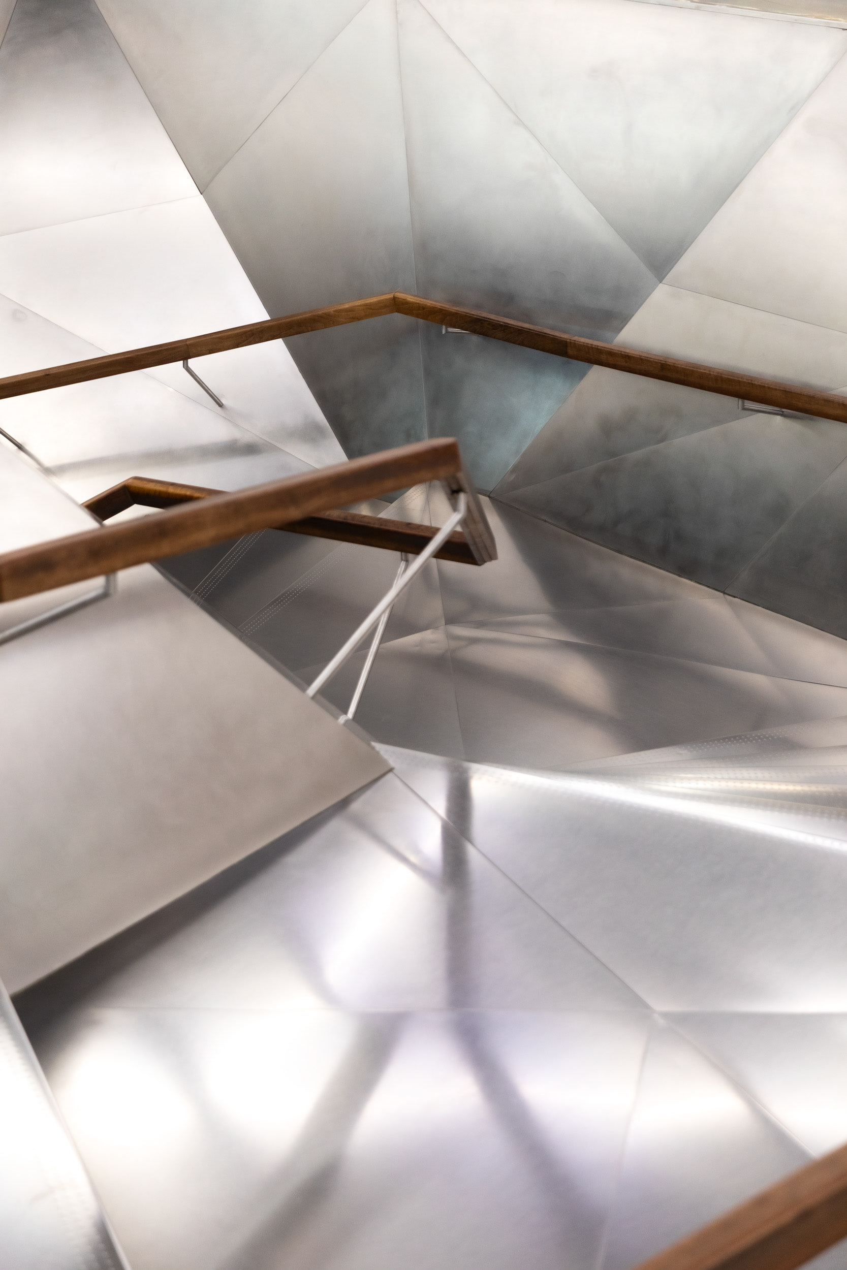 The folded stainless-steel staircase connecting the lobby to the bookshop and galleries above.