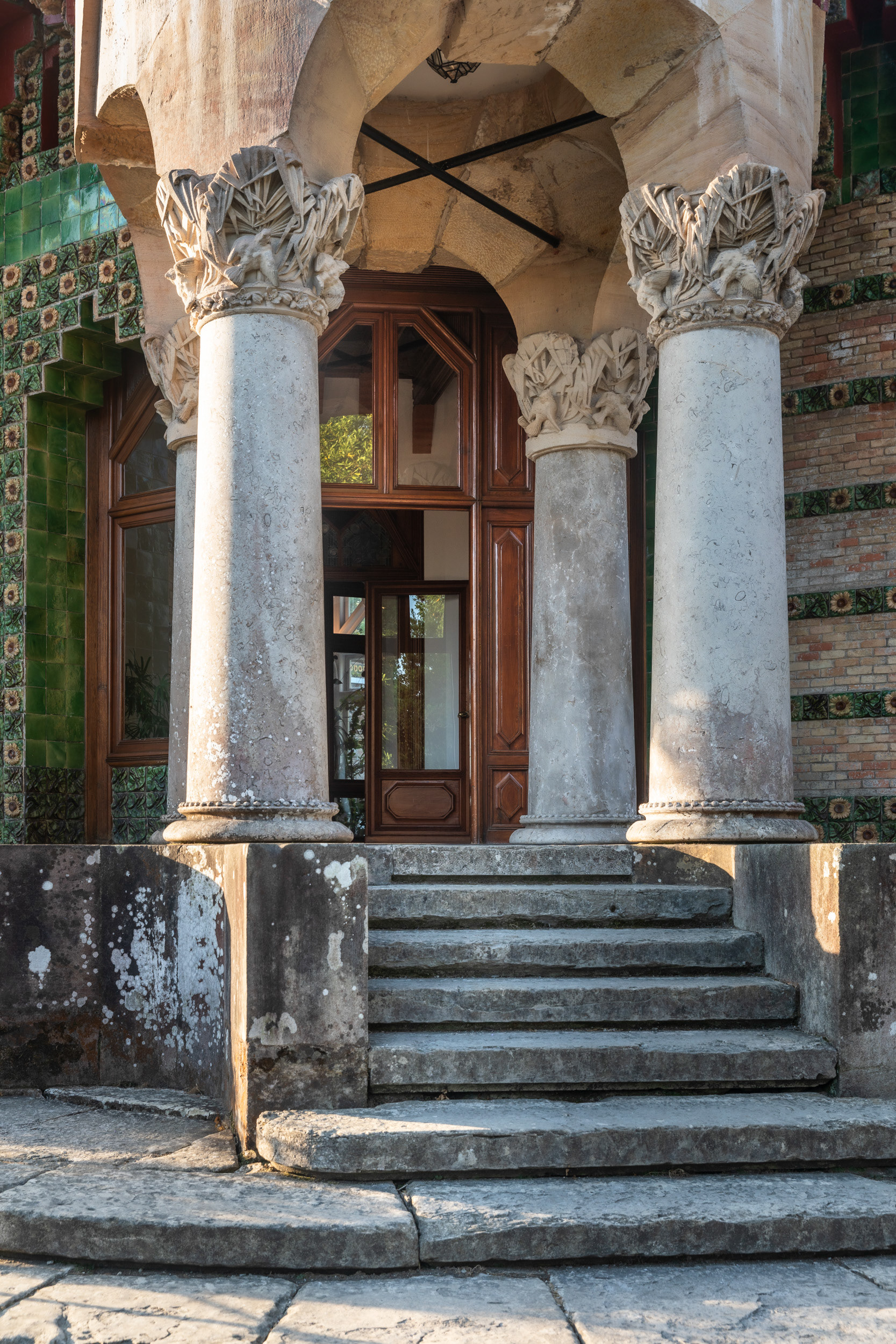 Four stone columns carry capitals carved with birds and palm leaves, and take the weight of the tower above.