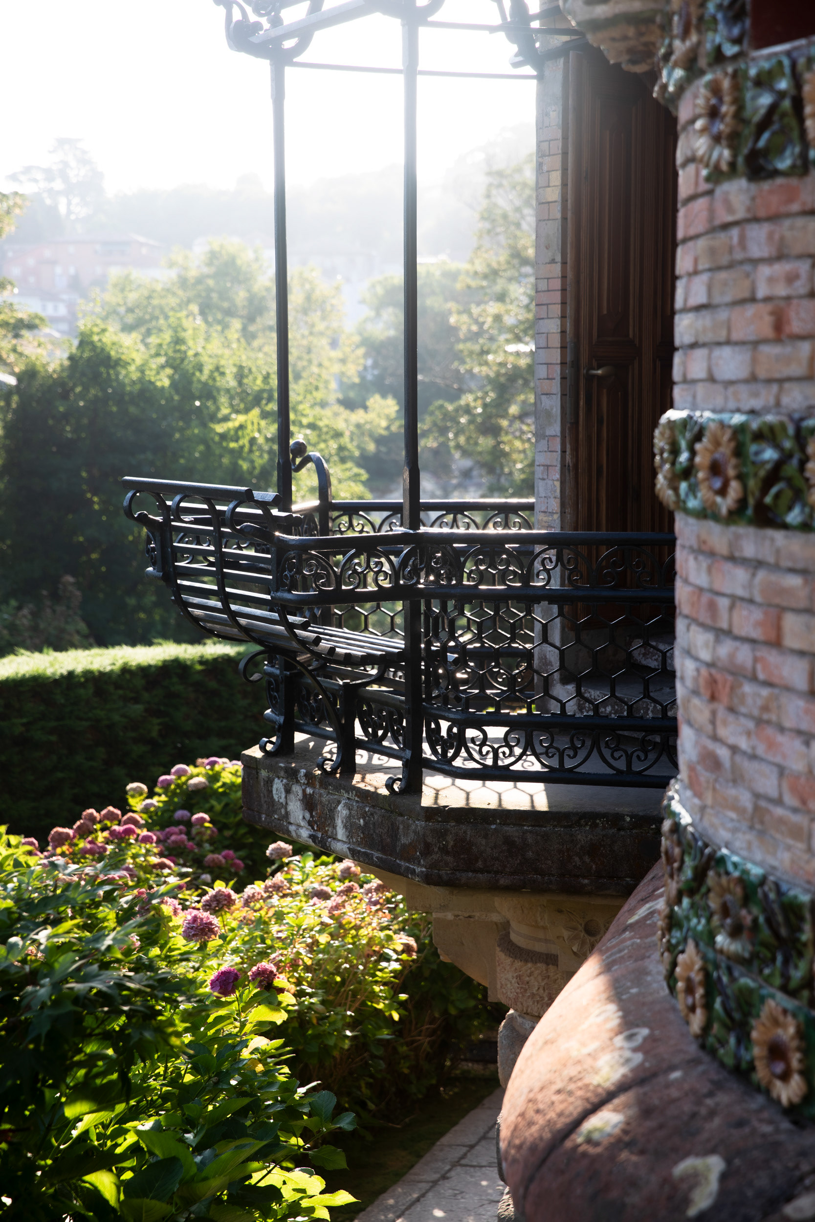 Iron balconies fold outward into a bench, under a pergola frame.