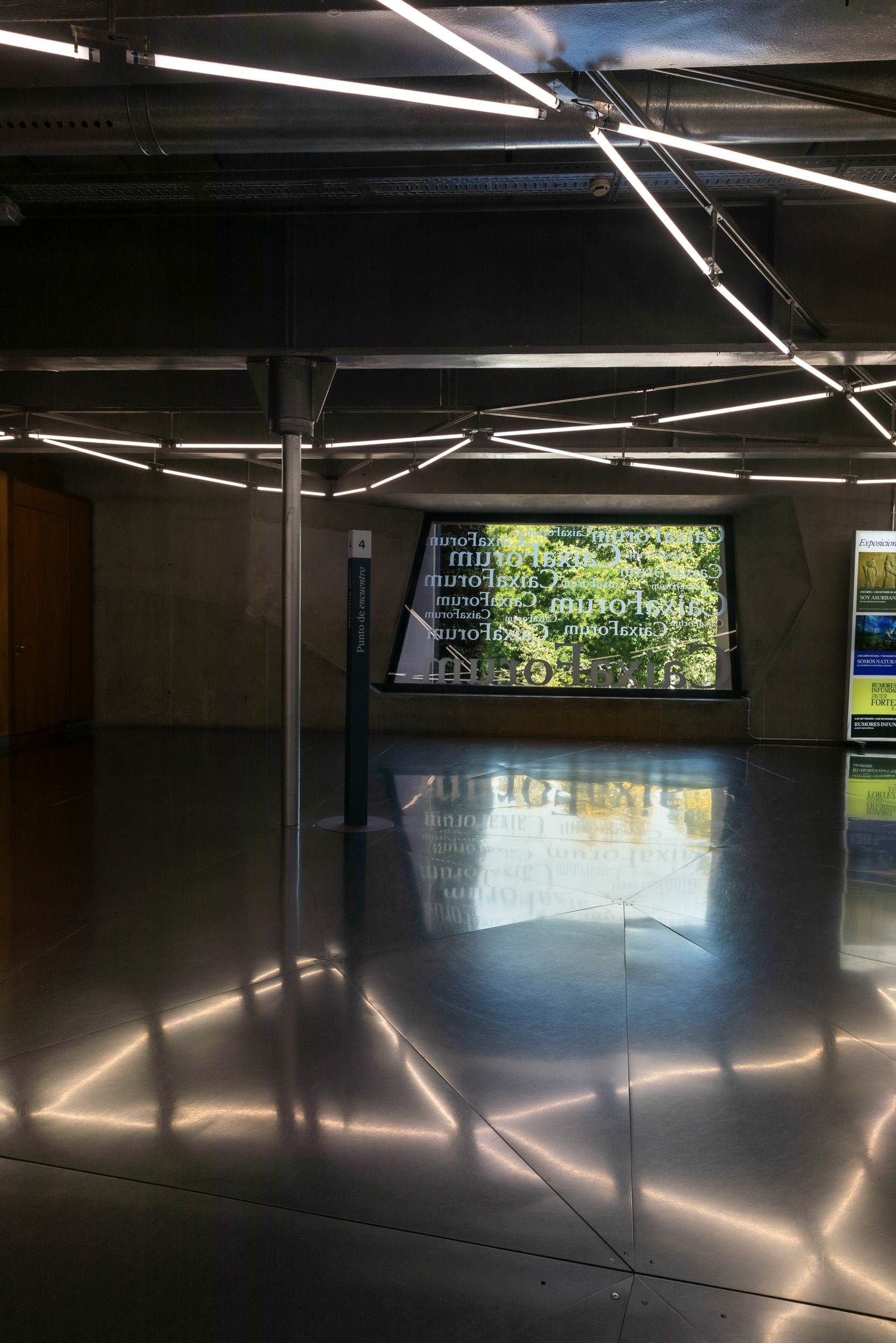 The ground-floor lobby. The "CaixaForum" lettering on the street-facing window reads in mirror-image from inside.