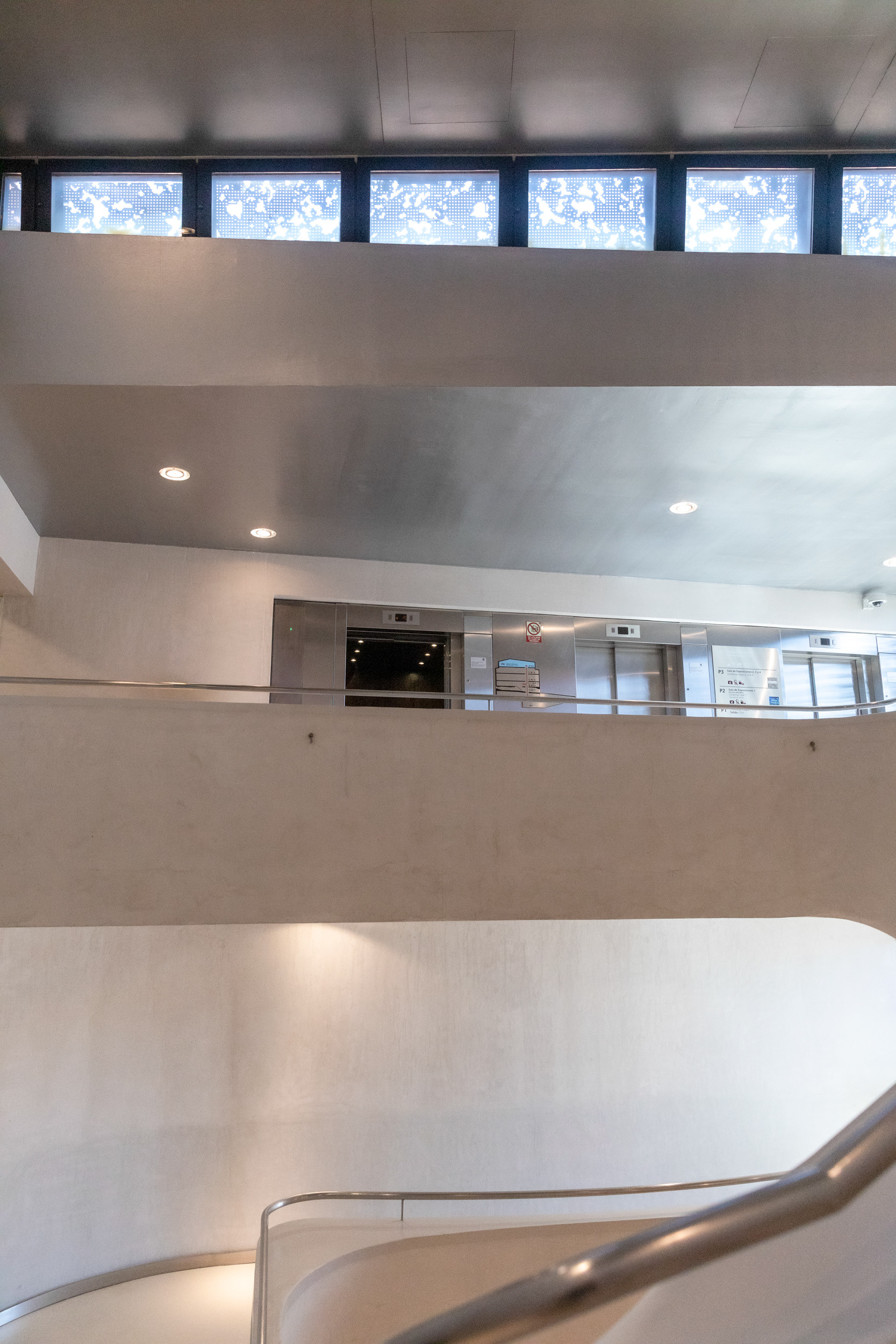 The lifts on one of the gallery levels, seen from the stairwell, below a run of clerestory windows.