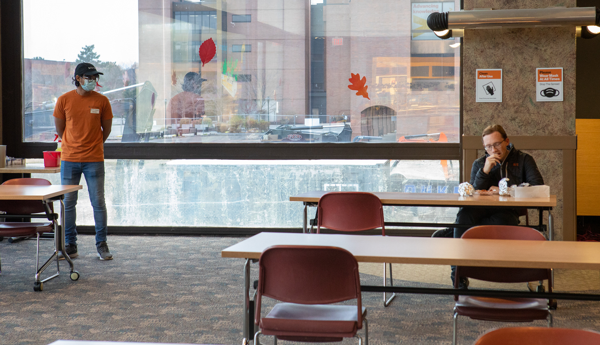 Prateek waits for a student to finish his lunch so he can wipe down the table on November 13, 2020. Prateek says "Oh Lord, oh Lord, yes things have changed! We have to clean after everyone gets up from a spot and this is a new position that we didn’t have before COVID."