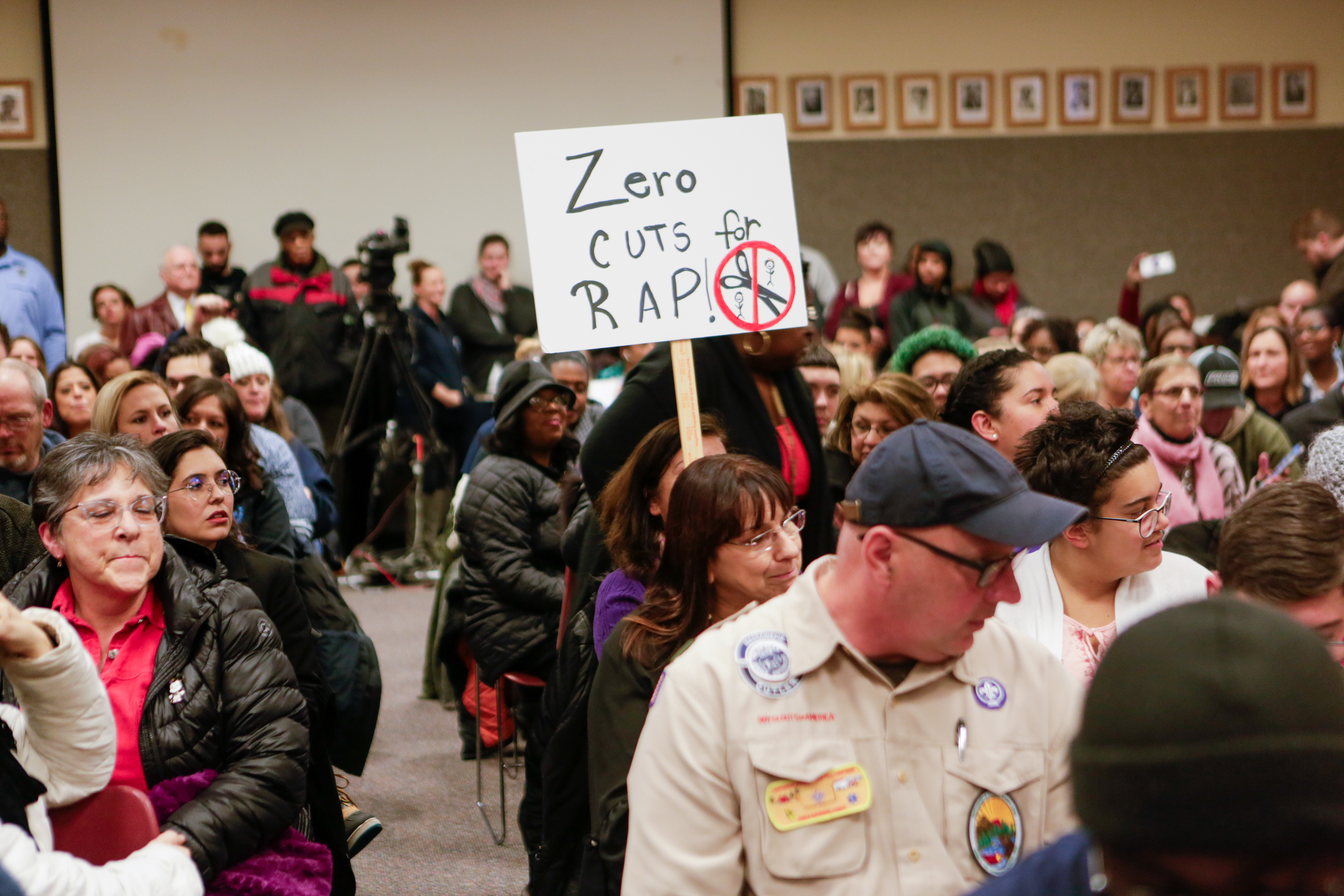 A member of the crowd attending the school board meeting holds a sign that reads “Zero Cuts for RAP!” December 5 2019 in Rochester N.Y.