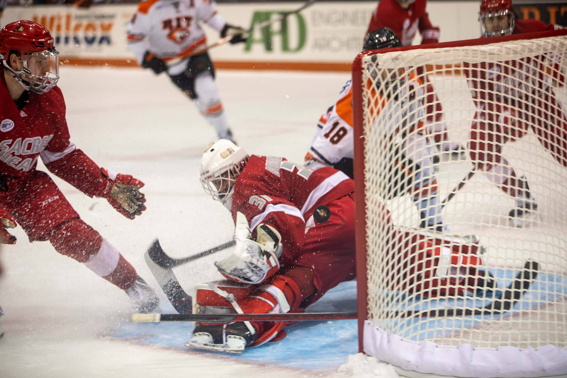 Sacred Heart University goaltender Justin Robbins (31) tries to stop the puck from entering the net, as fellow teammates watch during the Sacred Heart vs. Rochester Institute of Technology men’s Division 1 hockey game at the Gene Polisseni Center in Rochester, N.Y. on March 13, 2022. R.I.T. went on to defeat Sacred Heart 3-1.
