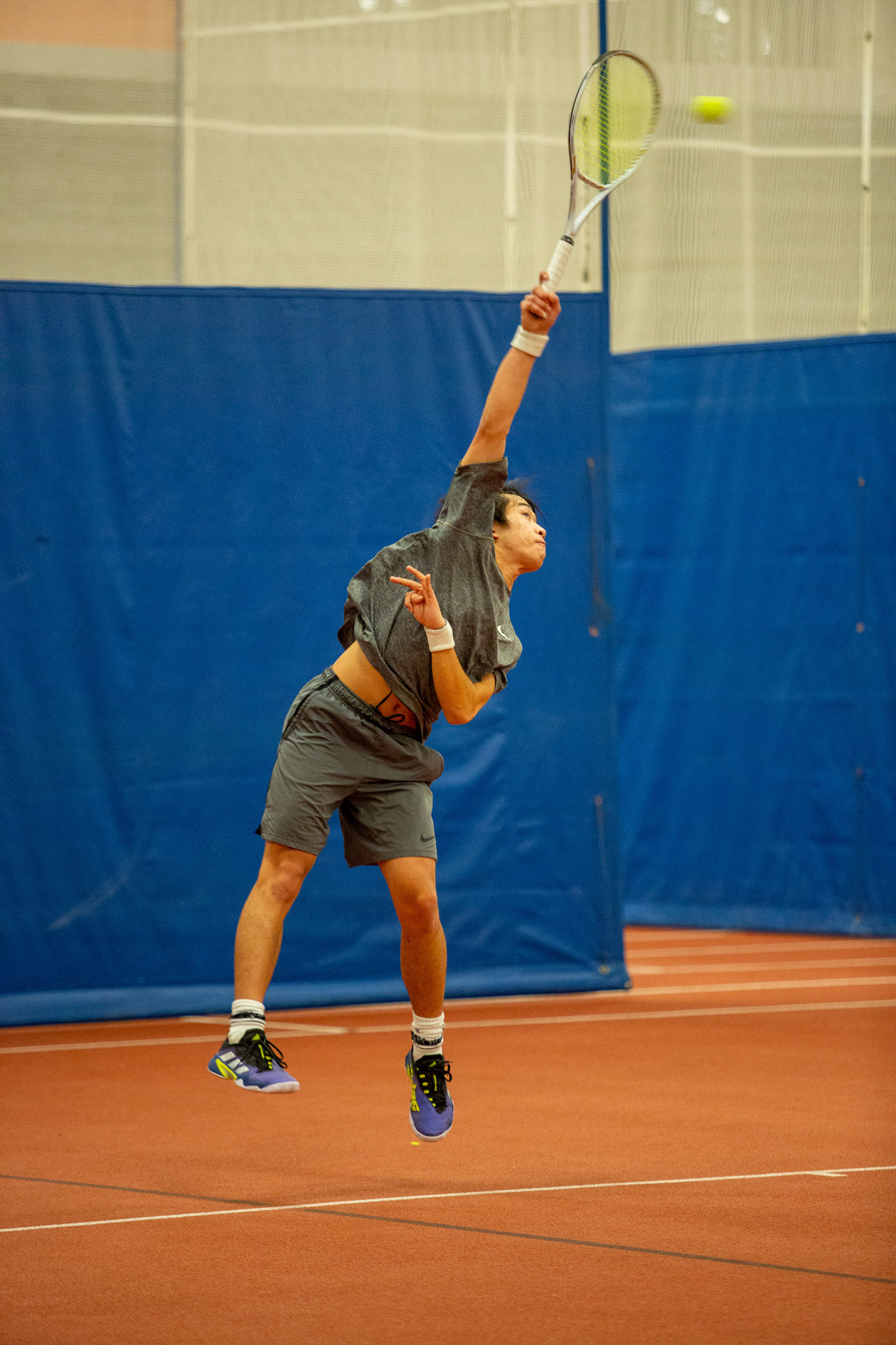 R.I.T. student Max Chang jumps when serving the ball in his tennis match against fellow R.I.T. student Verosh Jayanettie on February 27, 2022 in the Gordon Field House at the Rochester Institute of Technology in Rochester, N.Y.