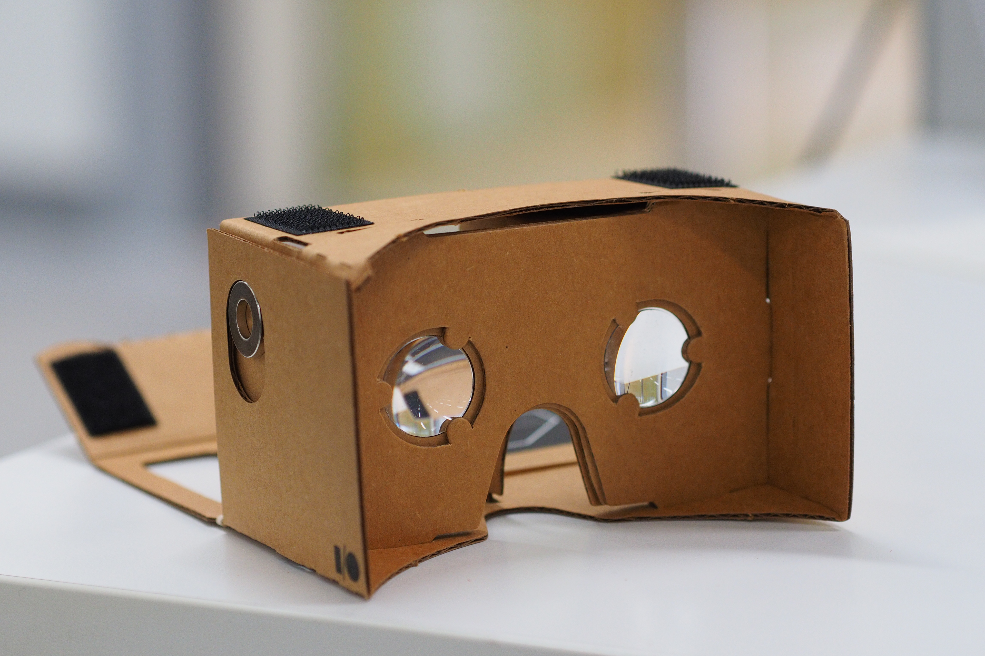 Google Cardboard opened, viewed from a 3/4 angle with the phone-compartment opened. This shows the velcro that holds the object together.