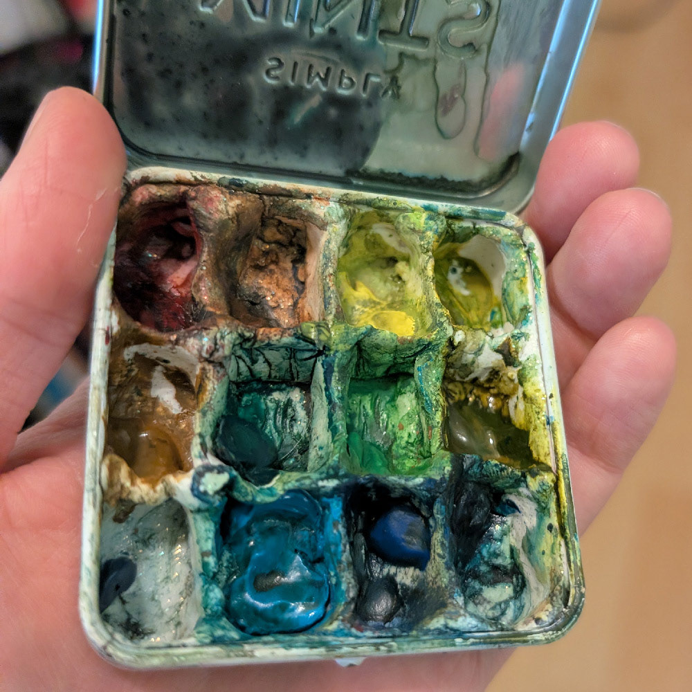 a shot inside my mint-tin watercolour palette. While ugly, the tin fits in my girl jeans front pocket. Here, I have a similar number of colours as my full palette, but with less mixing space.