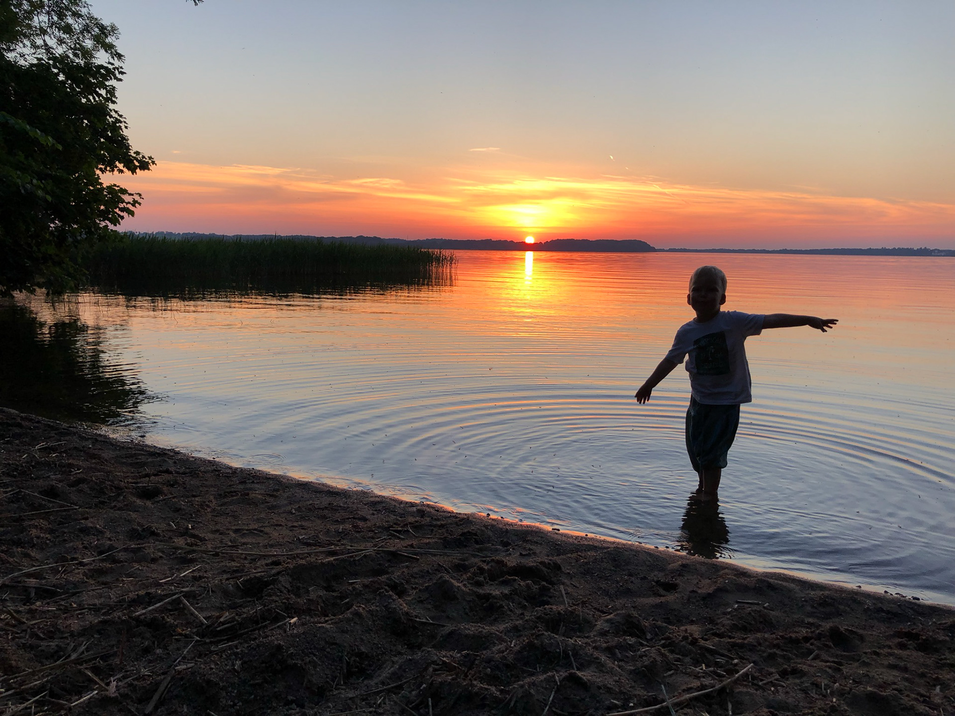 Jenny Johansson, Bilden är tagen i Höörs kommun. Jag är uppvuxen och numera också bosatt i Fogdarp, intill Ringsjön och älskar att ha sjön nära. Detta är en speciell plats för mig där jag otaliga gånger begett mig för att söka tröst, hämta energi och minnas. Här har jag gift mig och här har vi lekt och haft mysiga sommarkvällar sedan jag var barn. På bilden syns min son, 4 år gammal när bilden togs en sensommarkväll 2021.