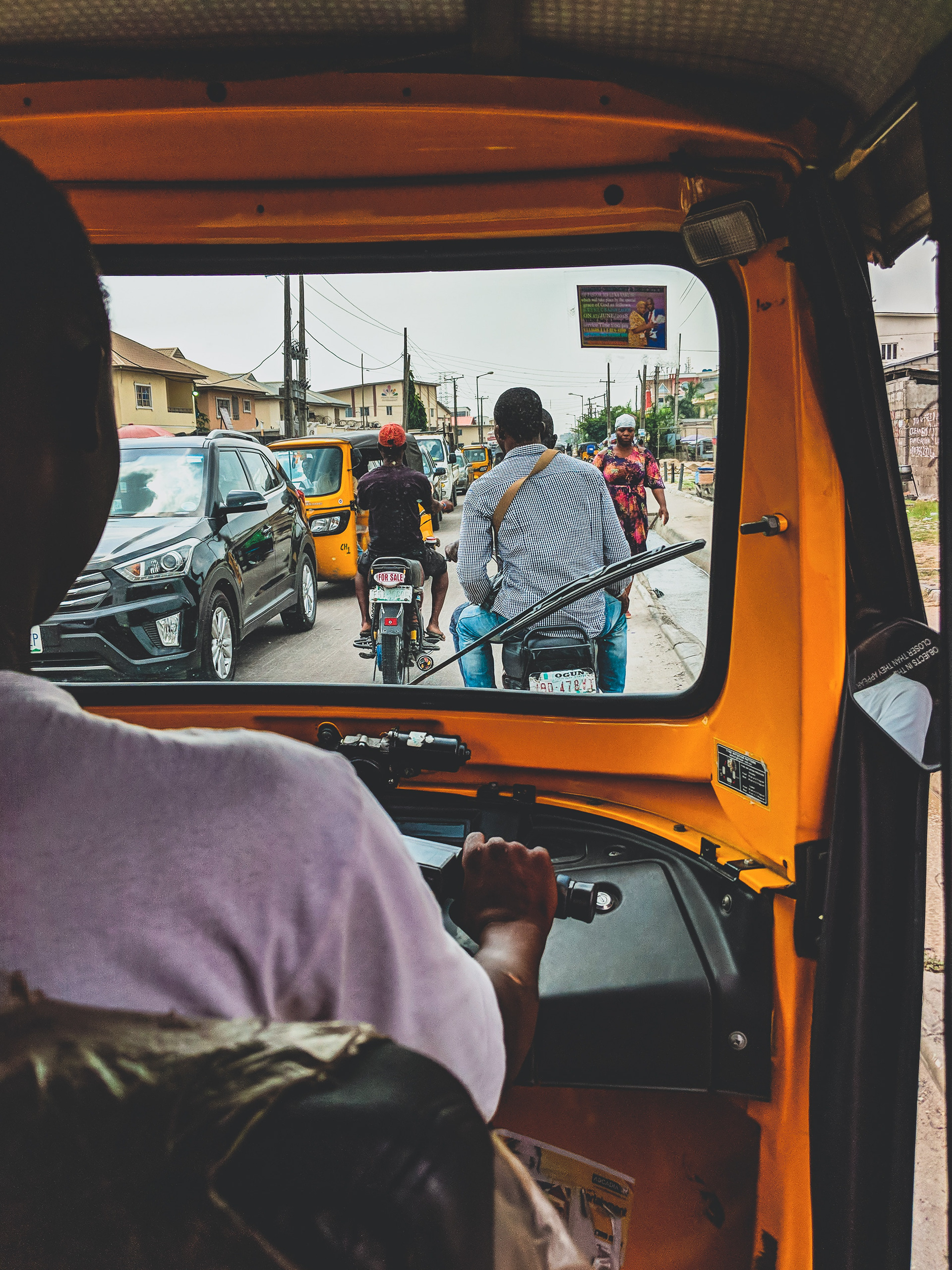 Man driving on crowded street in Africa behind cyclists