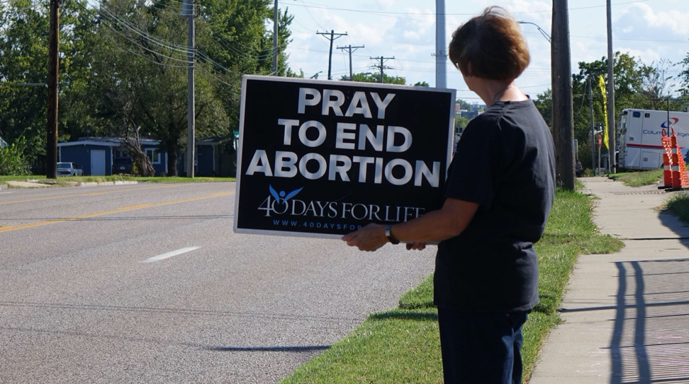 Sonia Potts holds up a sign on the sidewalk outside of Planned Parenthood as part of 40 Days for Life in Columbia, Mo., on Wednesday, Sept. 25, 2019. Cars driving past on busy Providence Road can see the activists holding signs like these until 40 Days for Life ends on Nov. 3.