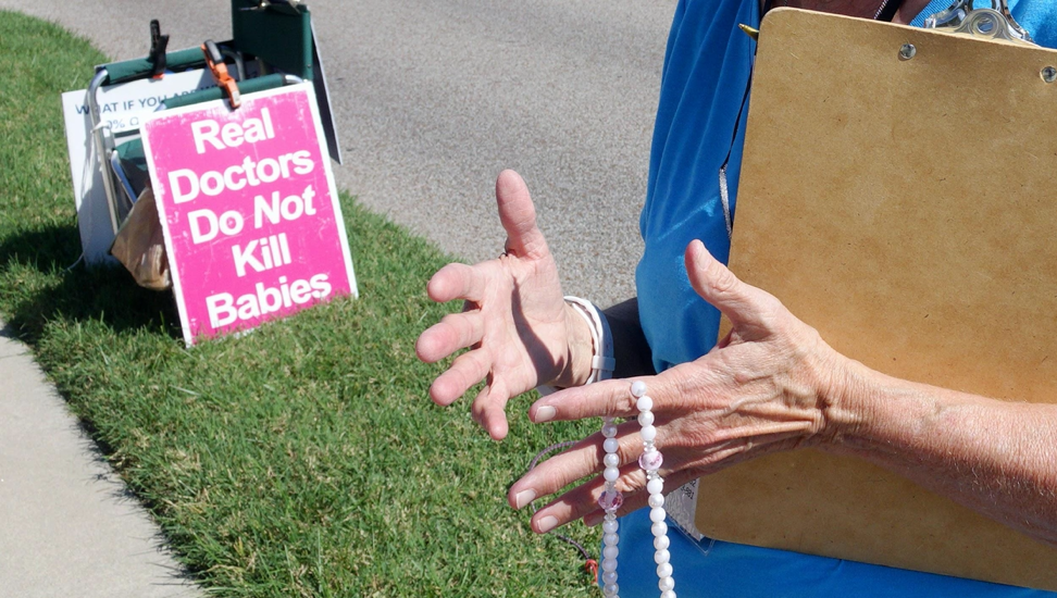 Carol Fick holds her rosary outside of Planned Parenthood in Columbia, Mo., on Monday, Sept. 30, 2019. The group held many signs like the one depicted outside of the clinic as a part of 40 Days for Life.