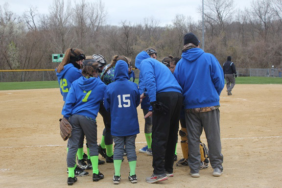 Kearney Intensity’s players and coaches gather for a huddle before one of their games on Saturday, April 14, 2018 in Blue Springs, Mo at Hidden Valley Softball Complex. The team shouted their unique chant before the huddle broke off and all the girls ran to their positions.