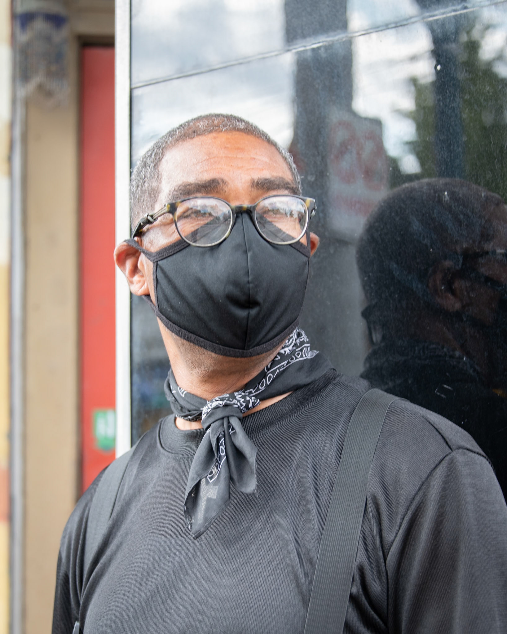 I introduced myself and began telling him about my project. I didn't get far.. He had plenty to say about face masks. I'll try to summarize: I went into the Dollar Store the other day to buy a pack of cigarettes. The store clerk asked for my ID. I gave it to him, then asked him, "how do you know that's me on that ID when I have a mask on?" "Oh, I know YOU", the clerk said, "you come in here all the time!"...  When people get stopped and are asked to describe someone, they just talk about what clothes somebody has on. They don't really see the person. They don't really look in the eyes and see who that person really is....   I used to be in the military. We used to wear masks that covered everything all around (he motioned with his hands all around his head). They covered everything but the eyes. Now, that's a mask! That's what masks should be!...   When we're out in public and around people, yes, we should wear masks! When we're home, take them off! Be with your family!   Finally, I said,  I'm not sure that I mentioned that I was hoping to take a photo of you. Would that be OK? He agreed, and immediately struck a pose, looking off into the distance. He looked deep in thought.  I asked if I could share the photo and comments on social media. "Oh, I'm not on social media. I don't believe in it.", he said. Hmm, I thought. "Does that mean you'd rather I not post any of this?" "No", he replied, "go ahead and post. I know lots of people on social media. Let them see it. And if you think about putting any of these photos in a gallery, I know a guy! (He told me a name and a gallery). You should reach out to him!"  I have no doubt he knows lots of people. This was one friendly #HumanBehindtheFaceMask !