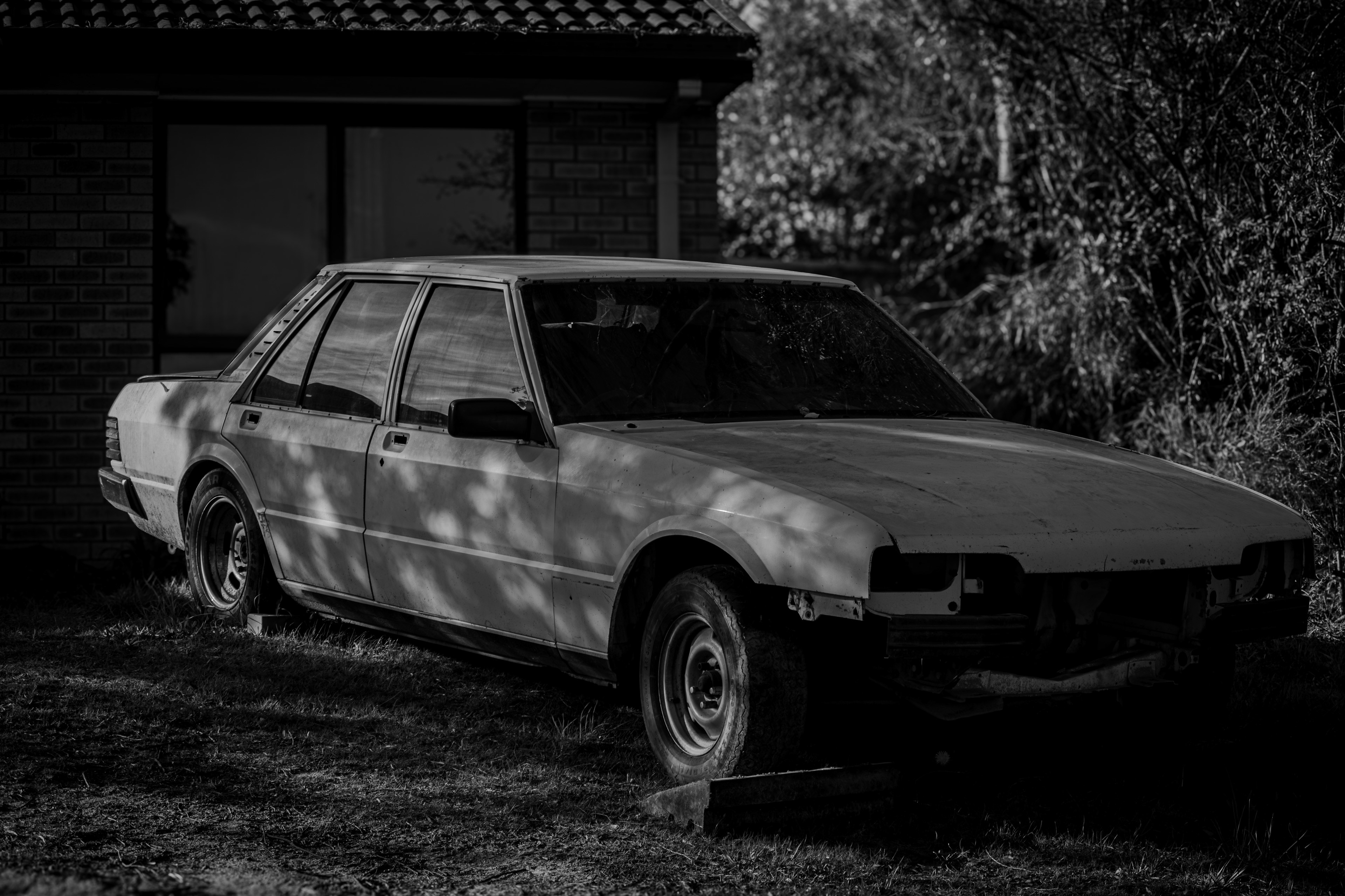 A car with missing parts against the front section of a residential  building