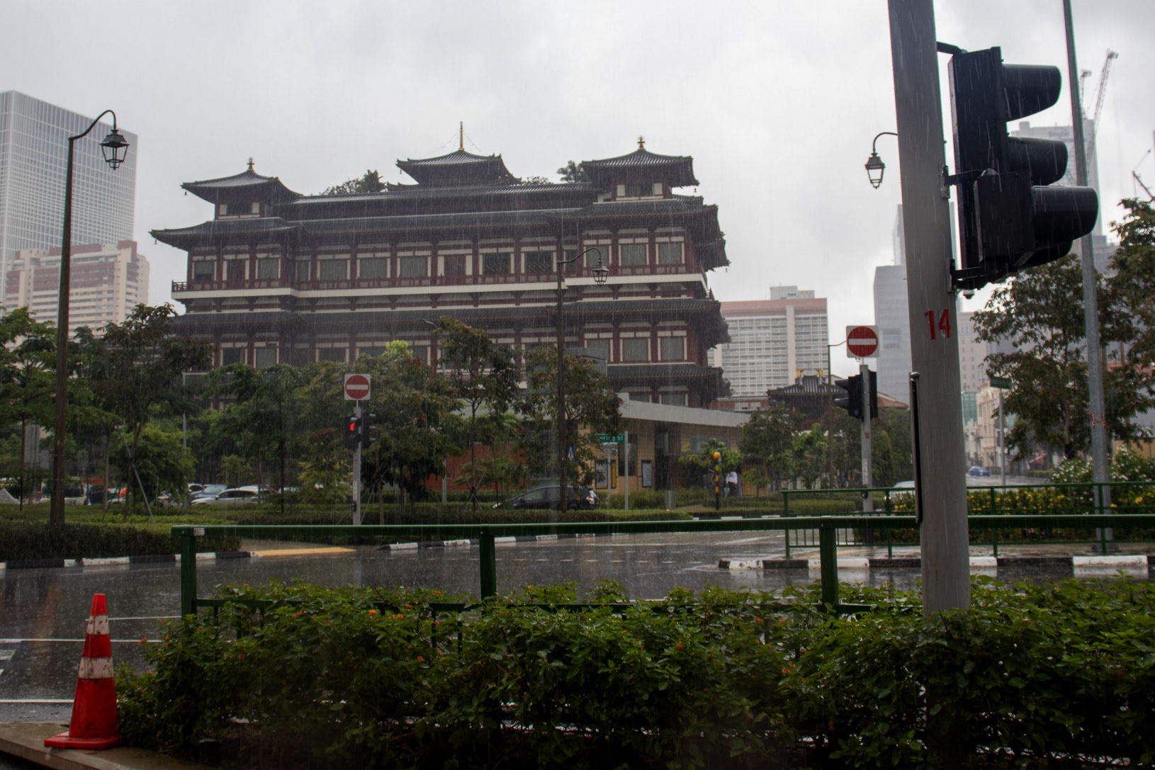 A rainy overcast day in the streets of Singapore with a chinese inspired building in the background