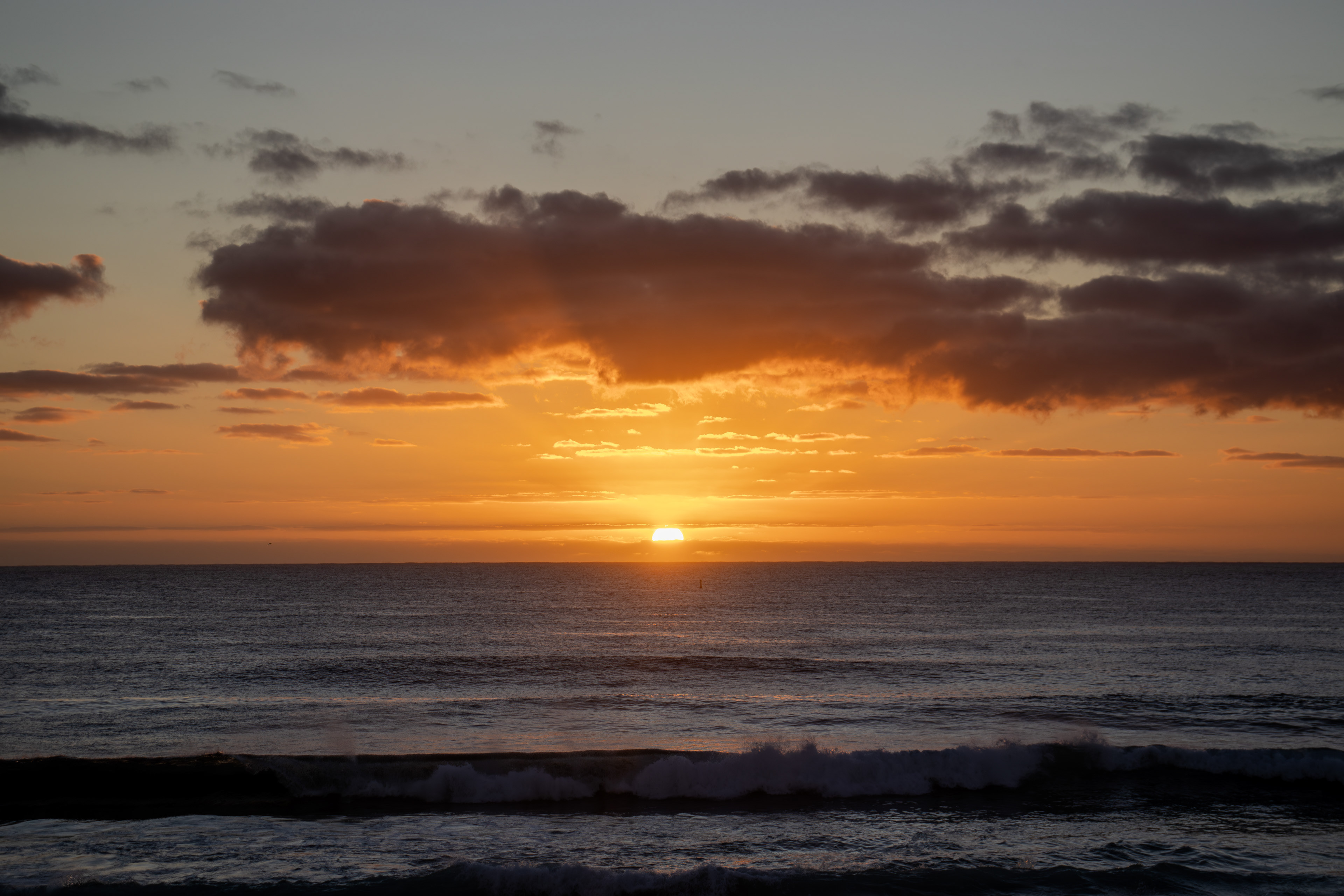 Sunrise along the ocean with darker clouds