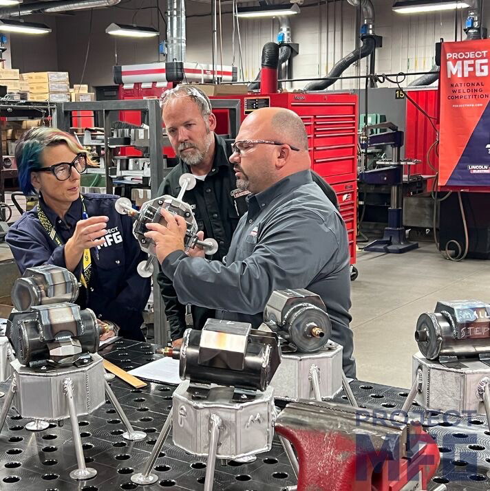 COMPETITION JUDGES REVIEWING COMPETITOR WELDMENTS