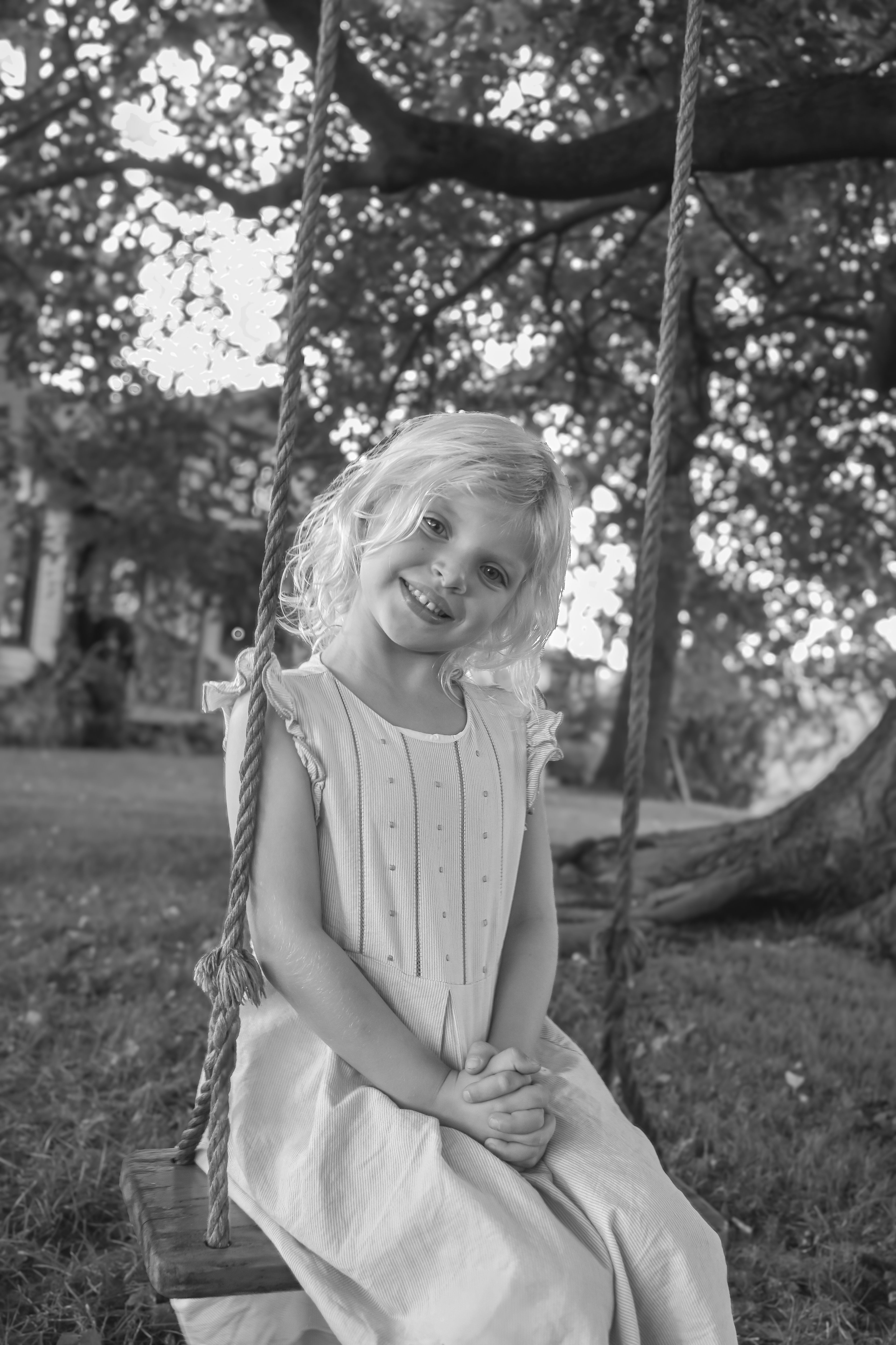 Little girls sits on a tree swing on her family flower farm at sunset during a family portrait session with photographer Lauren Nikiel Studio, a North Carolina (NC) photographer.