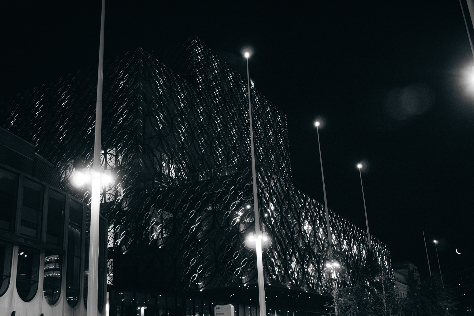 A black and white photo of birmingham library lit up at night.