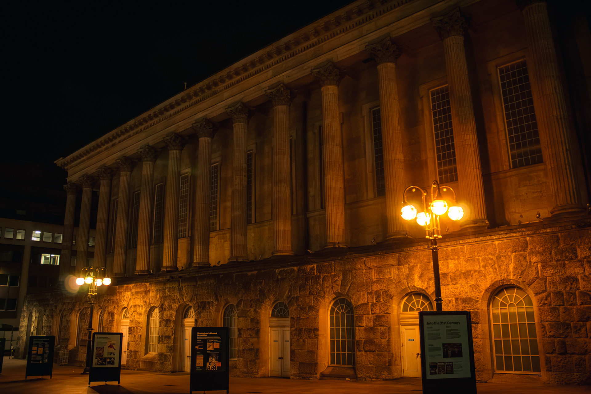 A photo of the side of birmingham town hall lit up at night.